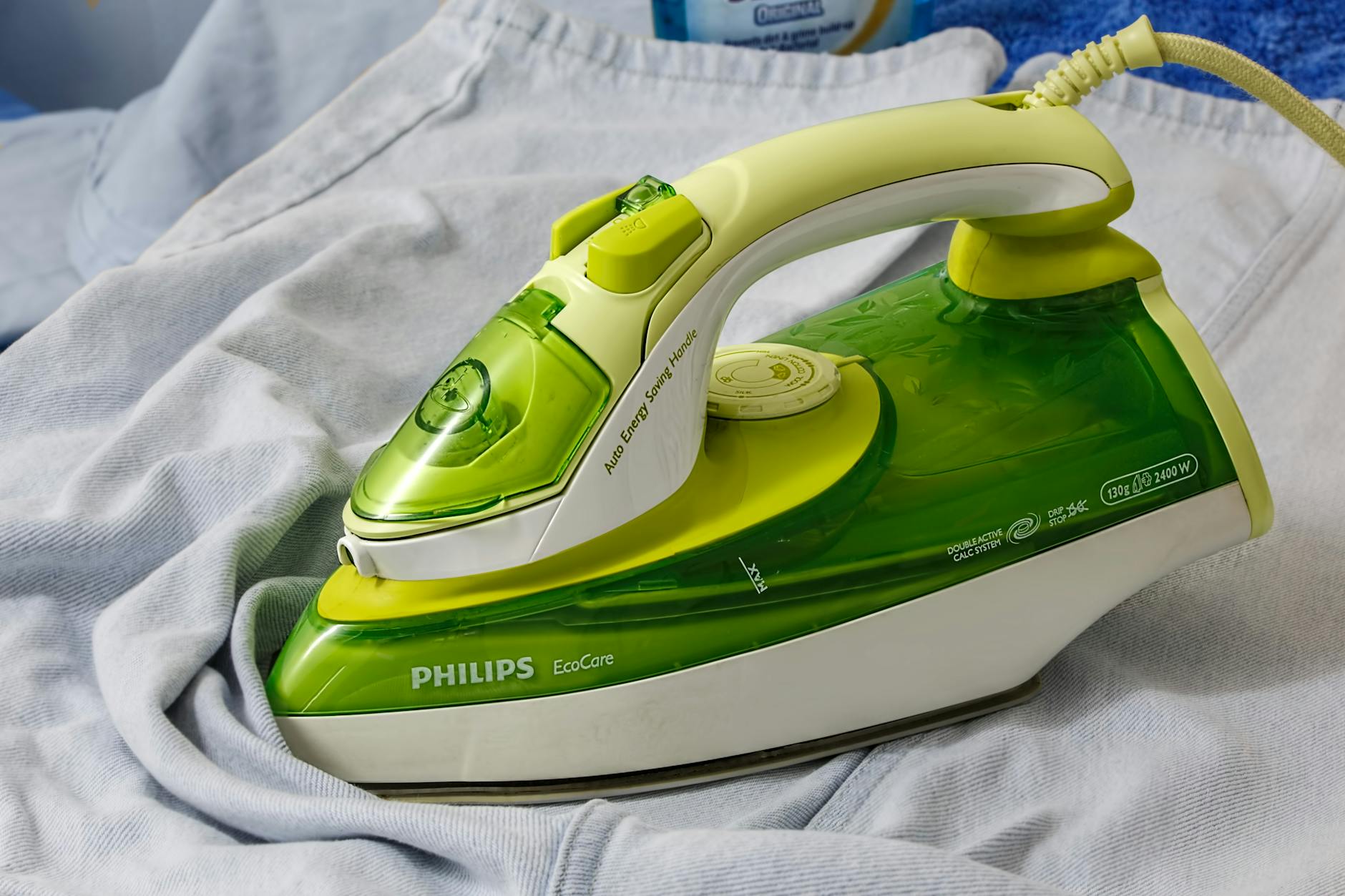 Green Philips EcoCare iron on a wrinkled shirt, ready for ironing. - spring chore division