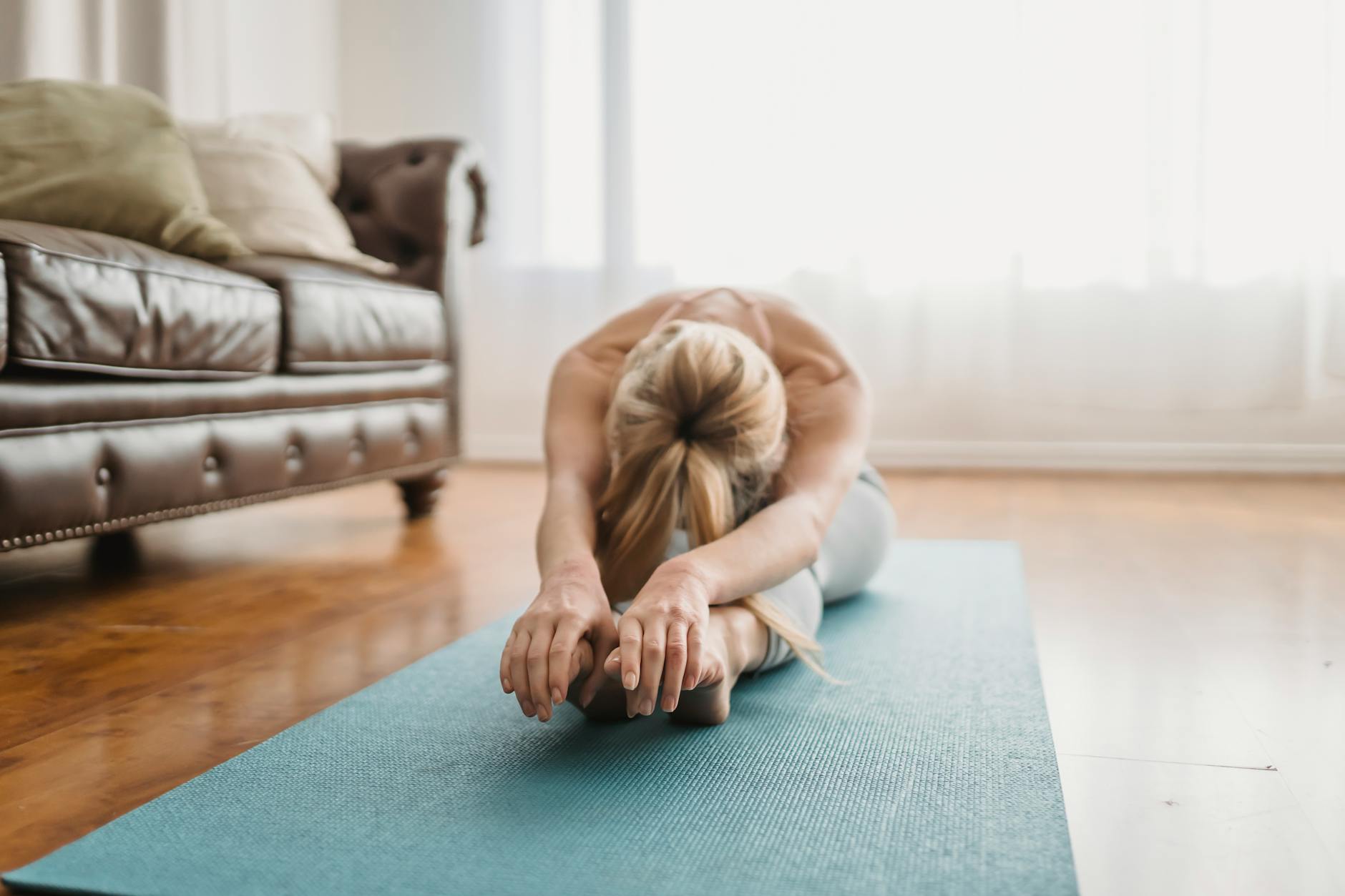 A woman performs a yoga stretch on a mat in a cozy living room, embracing wellness and relaxation. - spring forward mental health