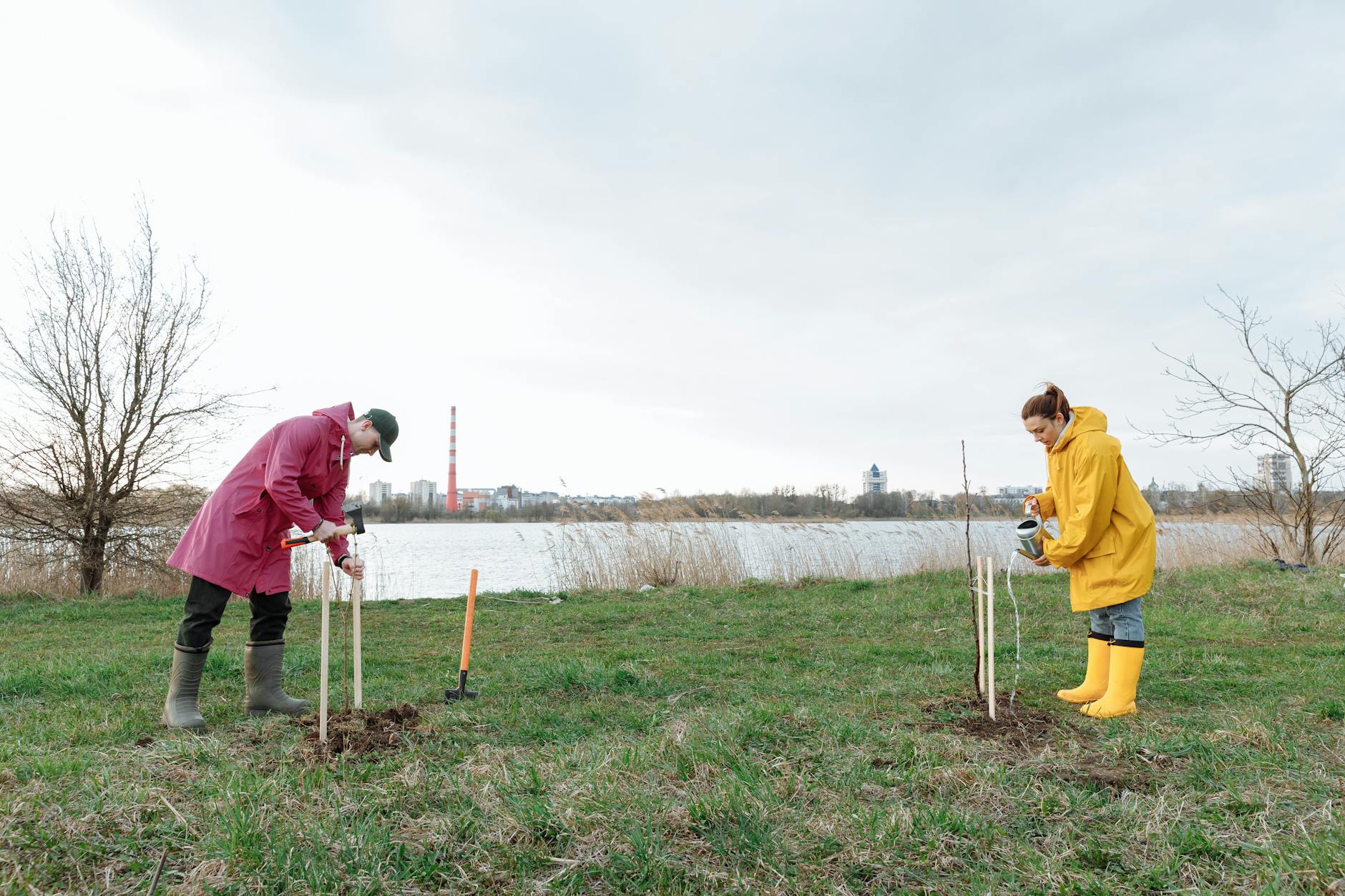 Two individuals planting trees by a riverside, promoting environmental conservation. - spring growth spurt communication