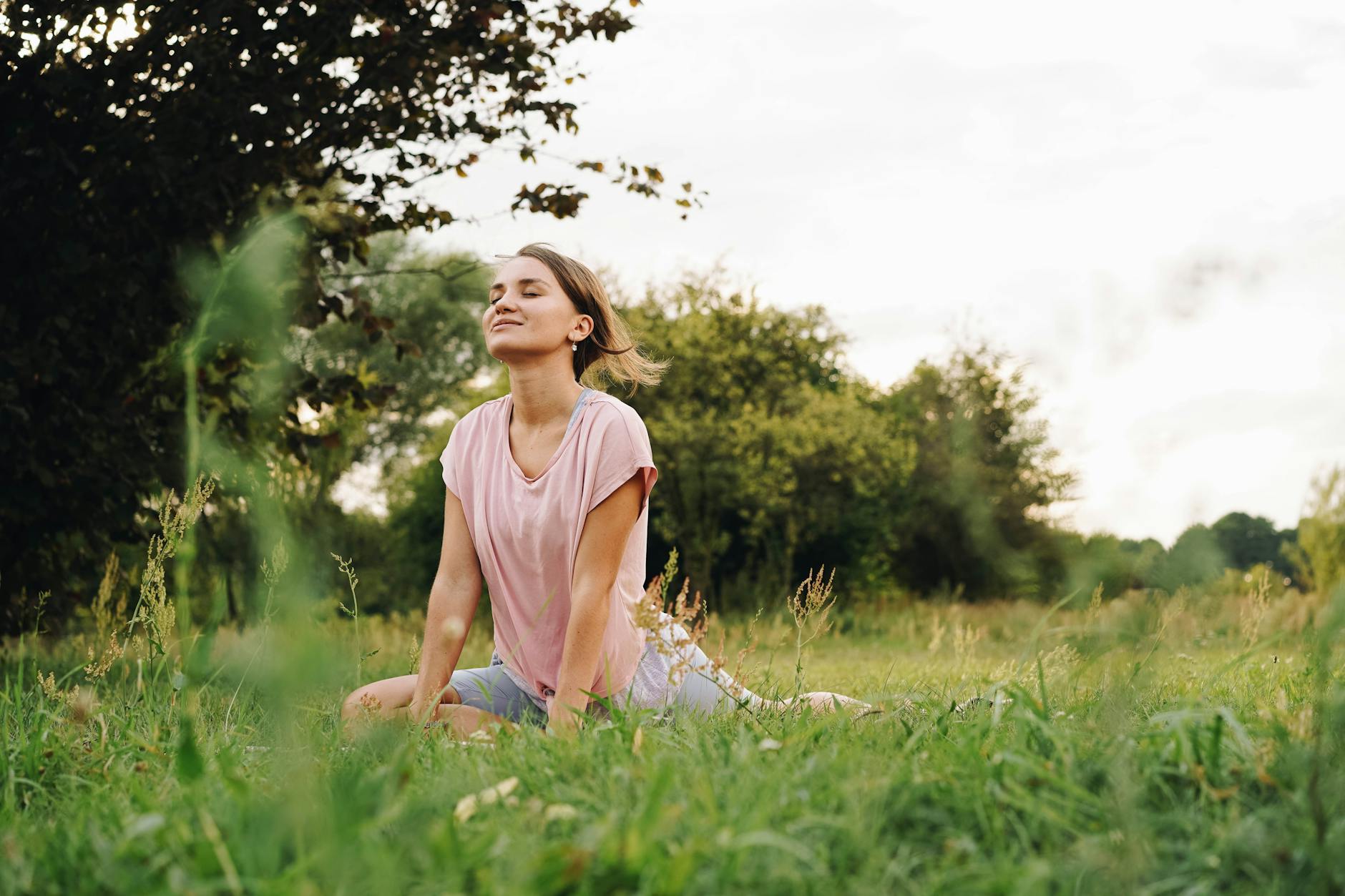 Woman practicing yoga in a serene park setting, signifying peace and mindfulness. - spring lethargy mindfulness
