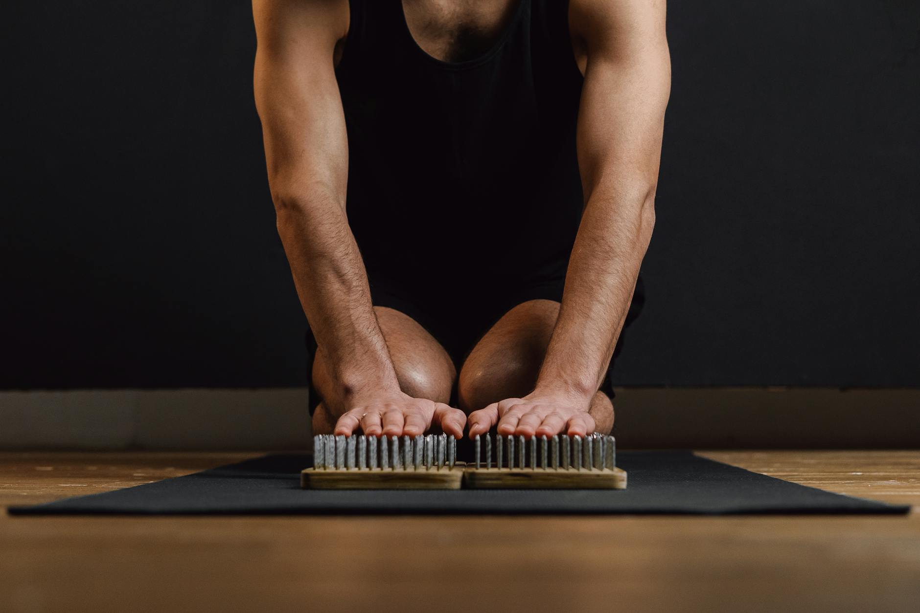 Adult man kneeling on a yoga mat practicing mindfulness with a sadhu board. - spring lethargy mindfulness