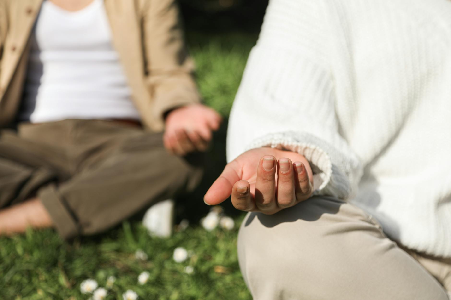 Two people meditating outdoors, focusing on hands in a peaceful setting. - spring lethargy mindfulness