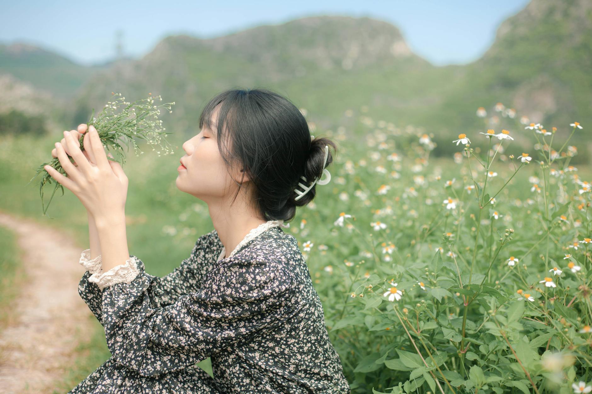 Woman in floral dress enjoying a serene moment in a green flower field. - spring melancholy therapy