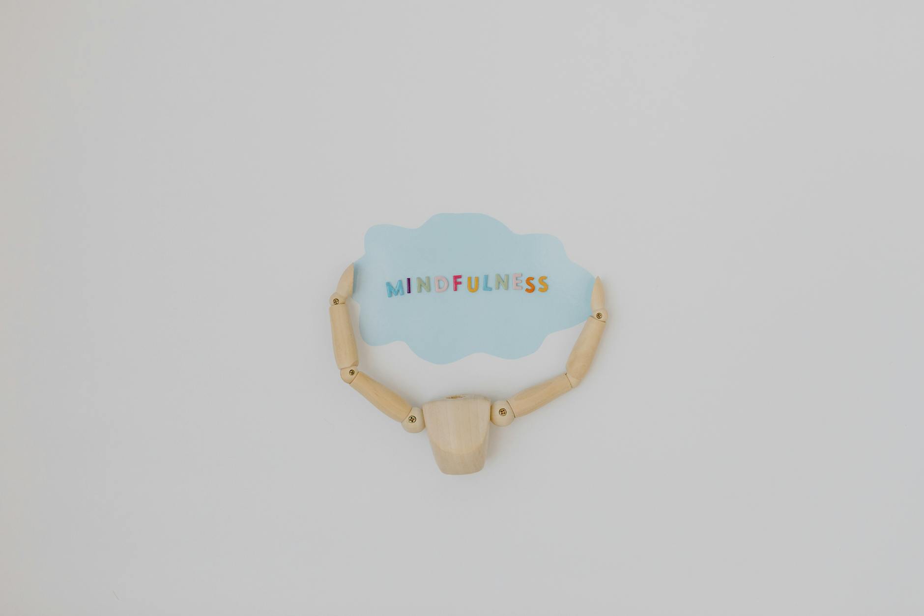 Minimalist image of a wooden figure holding a speech bubble saying 'Mindfulness'. - spring mental clarity