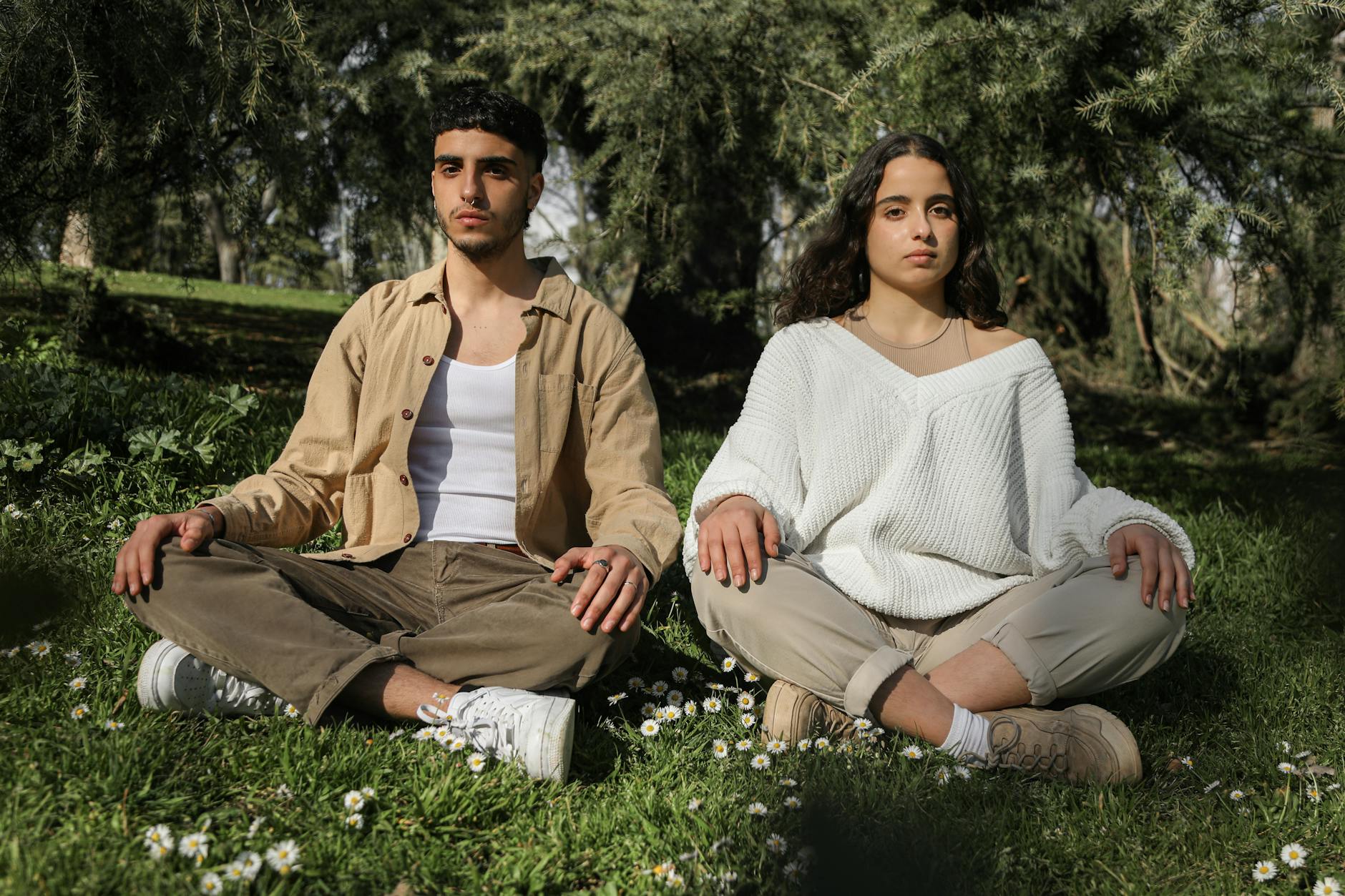 Two young adults meditating in a serene outdoor setting, surrounded by nature. - spring mental reset