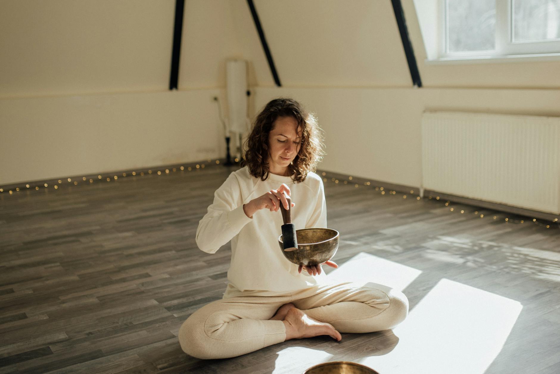 Serene woman meditating indoors with a Tibetan singing bowl, capturing tranquil vibes. - spring mindfulness practices