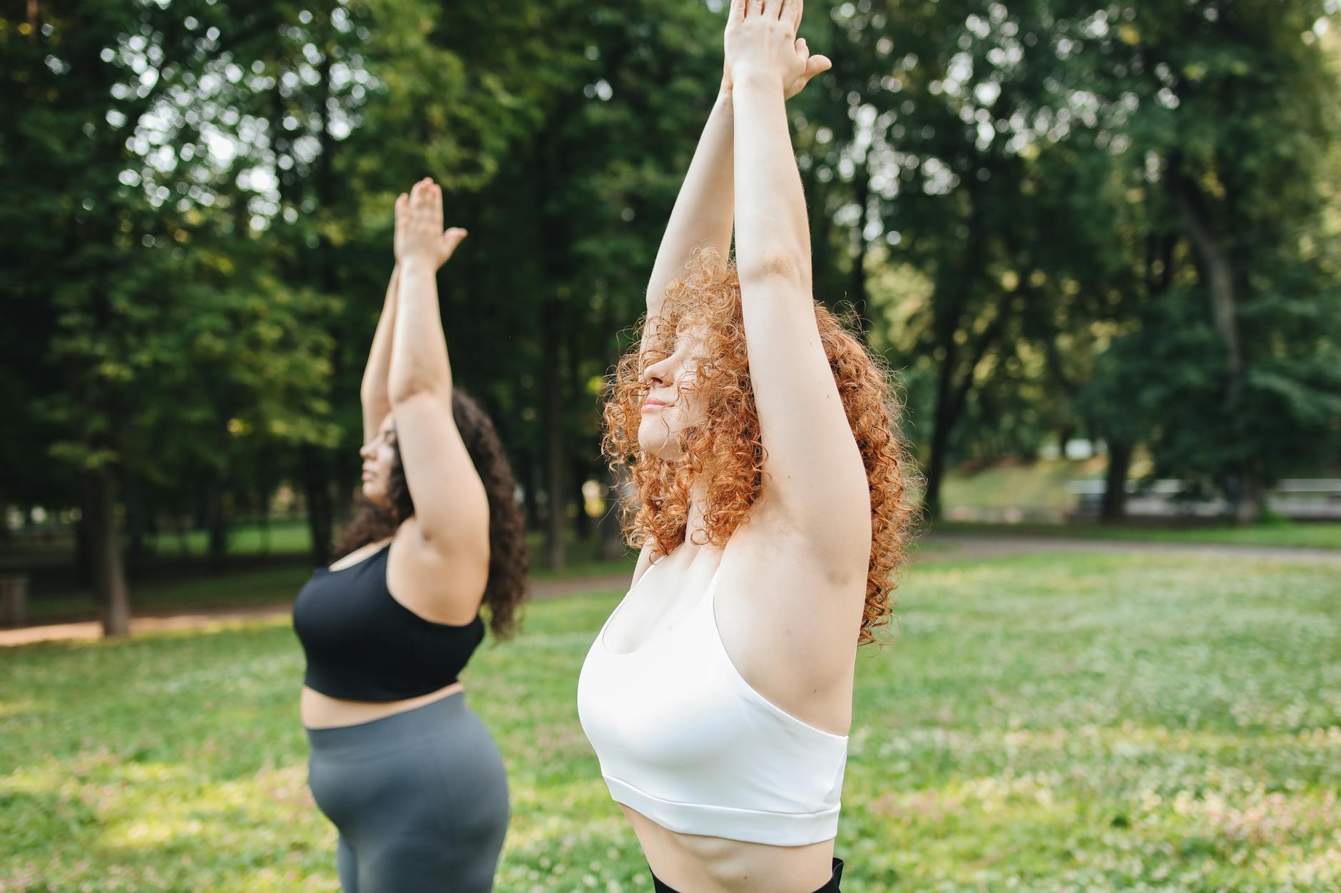Two women enjoying a yoga session in a lush green park, embracing a healthy lifestyle. - spring outdoor activities mental health