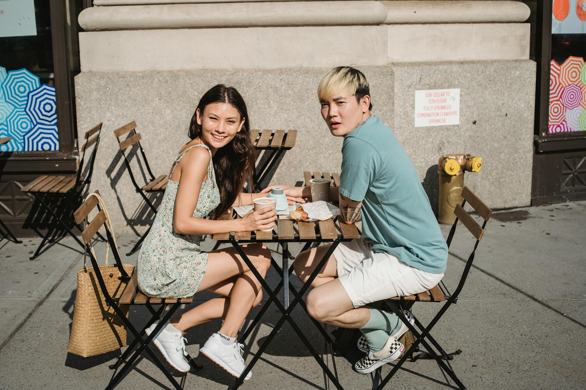 A young couple sits outdoors, sharing coffee and snacks, enjoying a sunny day. - spring outdoor date ideas