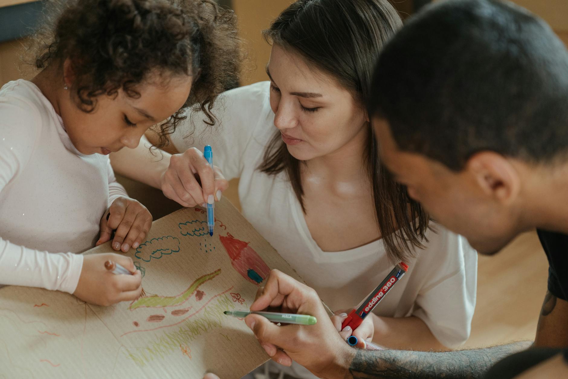 A family drawing together on cardboard, expressing creativity and spending quality time. - spring parenting tips