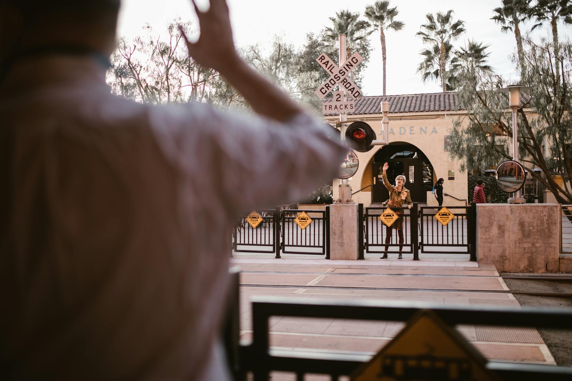 Two friends reunite at a train crossing, capturing a joyful moment in Pasadena. - spring relationship goals