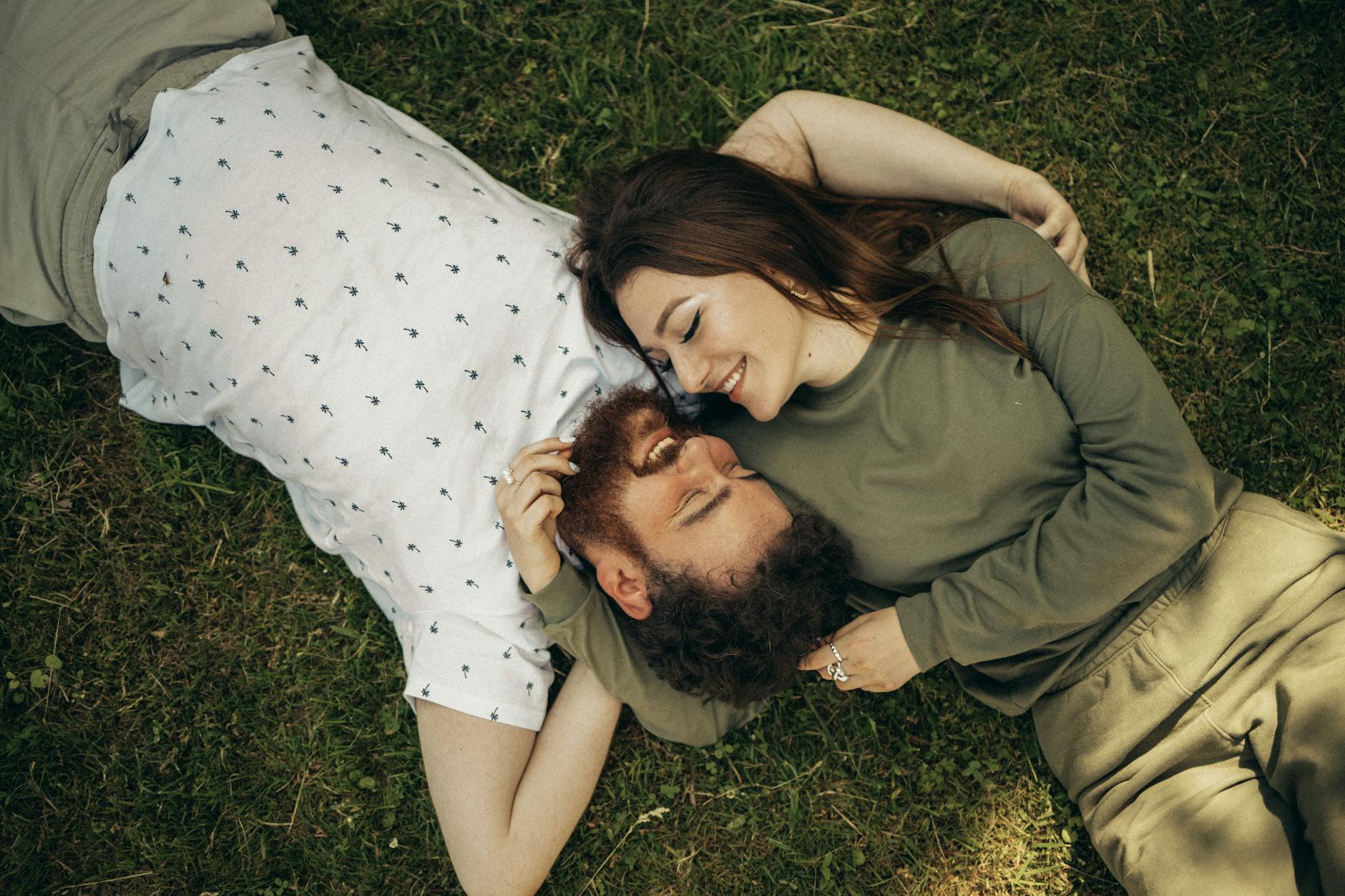 Happy couple lying on the grass, embracing and smiling, enjoying a peaceful moment outdoors. - spring relationship reconnection