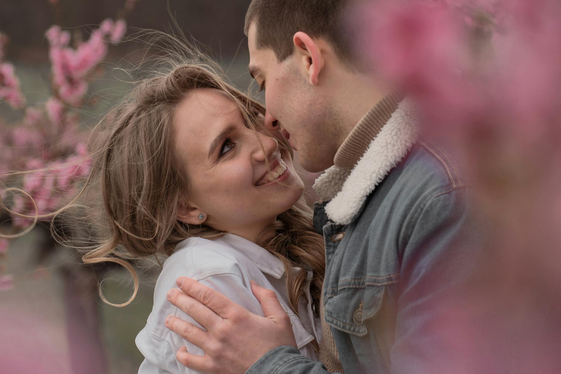 Happy couple embracing in a field with pink spring flowers, exuding love and joy. - spring relationship reset