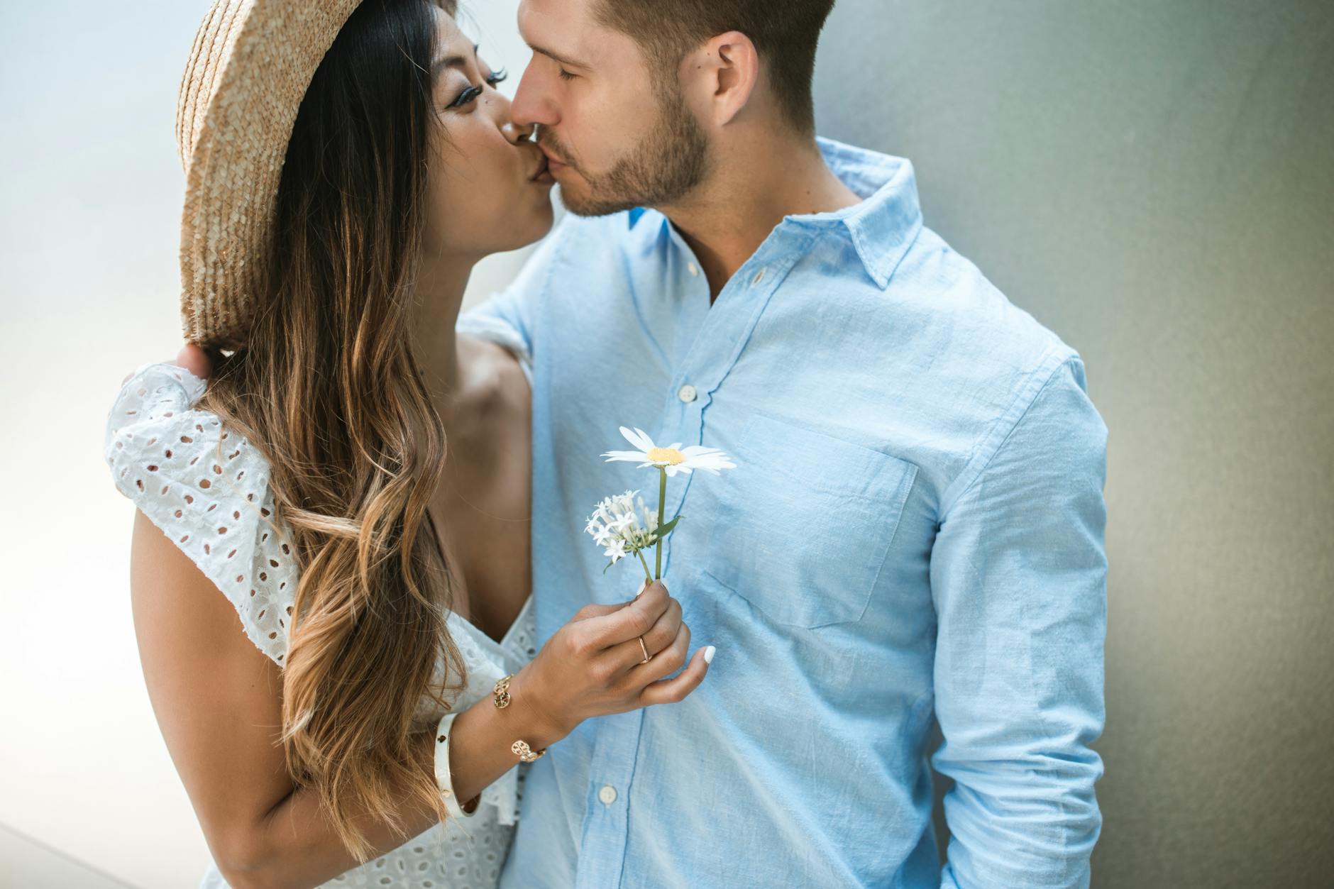 Couple kissing with flowers, wearing light clothing. Shows love and romance. - spring relationship reset