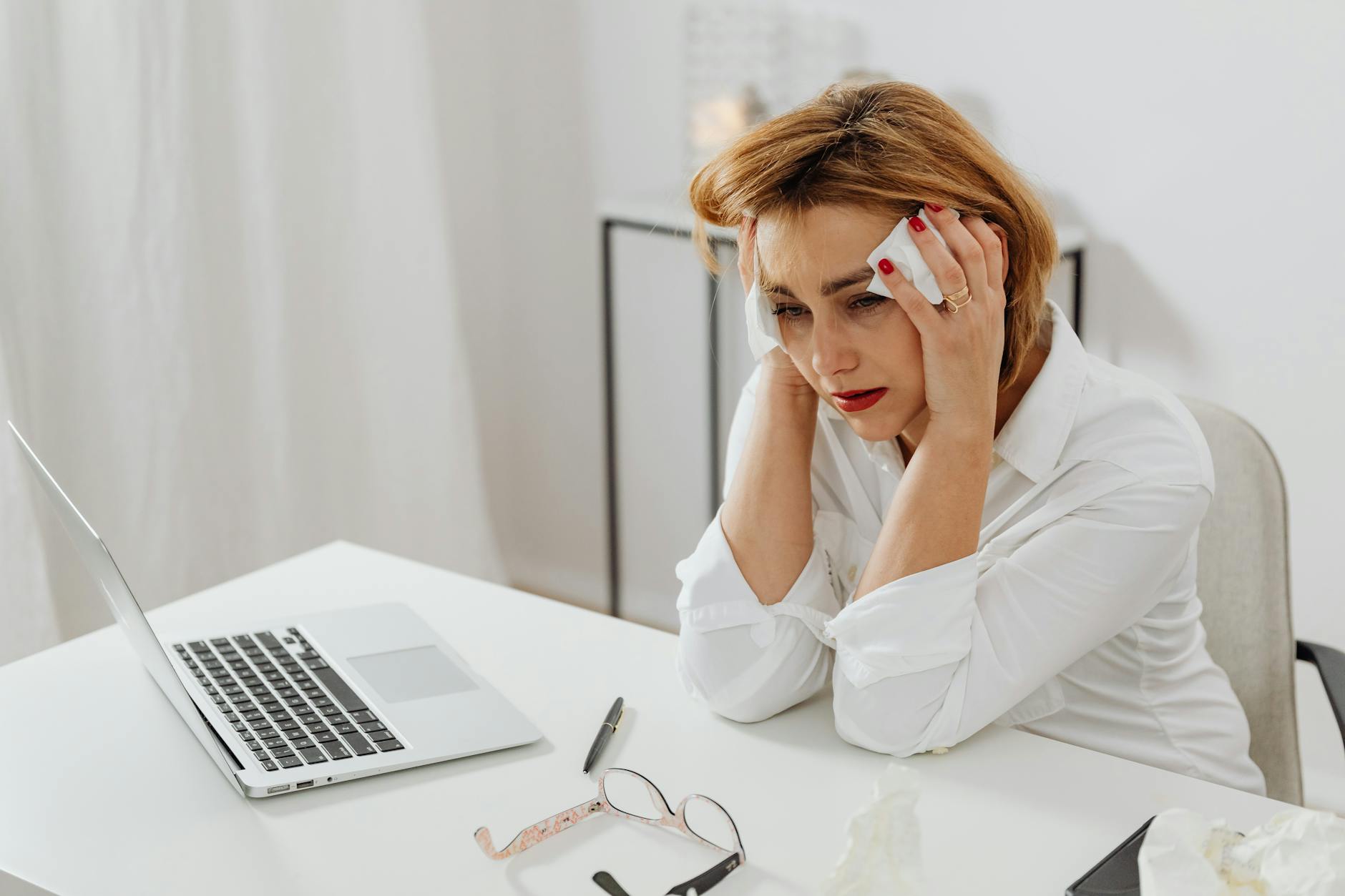 A woman in distress at her office desk, surrounded by tissues and a laptop. - spring stress relief