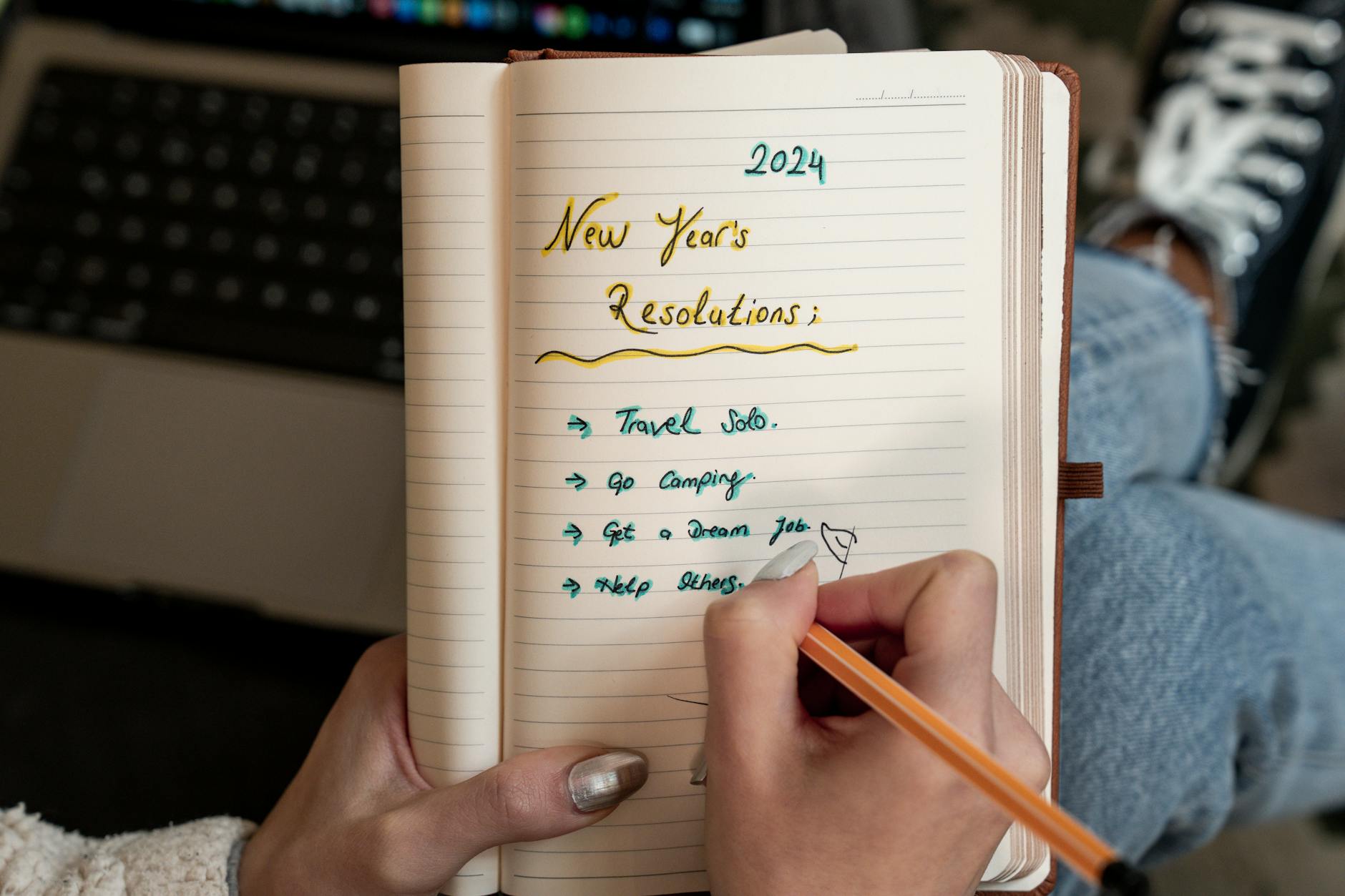A person writes 2024 New Year's resolutions in a notebook. Concept of planning and personal goals. - story resolution meaning