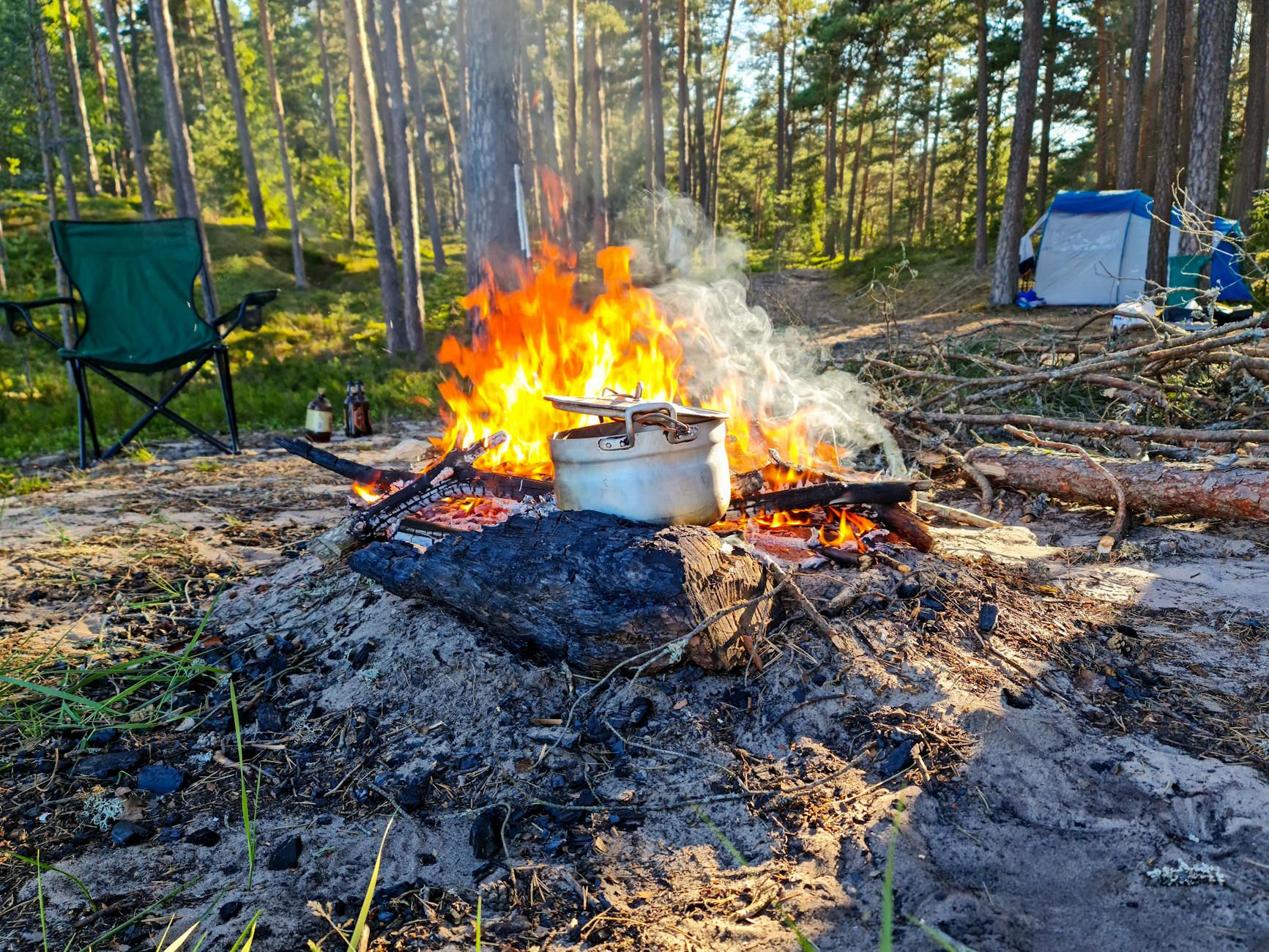 A calm camping scene with a vibrant campfire and cooking pot in a wooded area. - summer camp transition