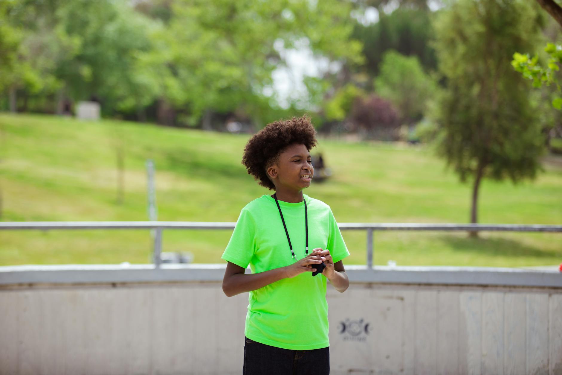 A teenager in a neon green shirt enjoys outdoor activities at the park on a sunny day. - summer camp transition
