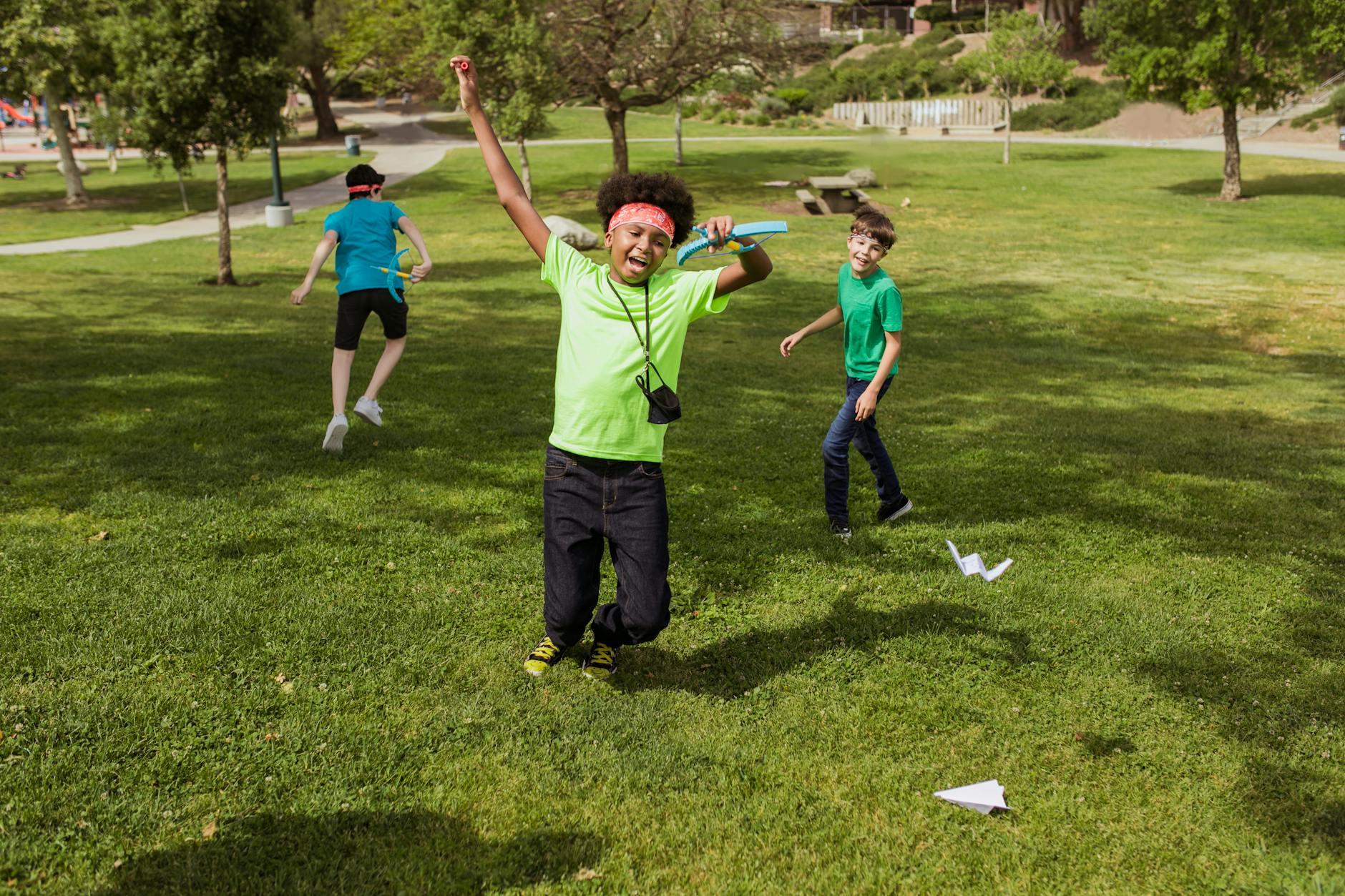 Kids having fun outdoors at summer camp playing with paper airplanes. - summer camp transition