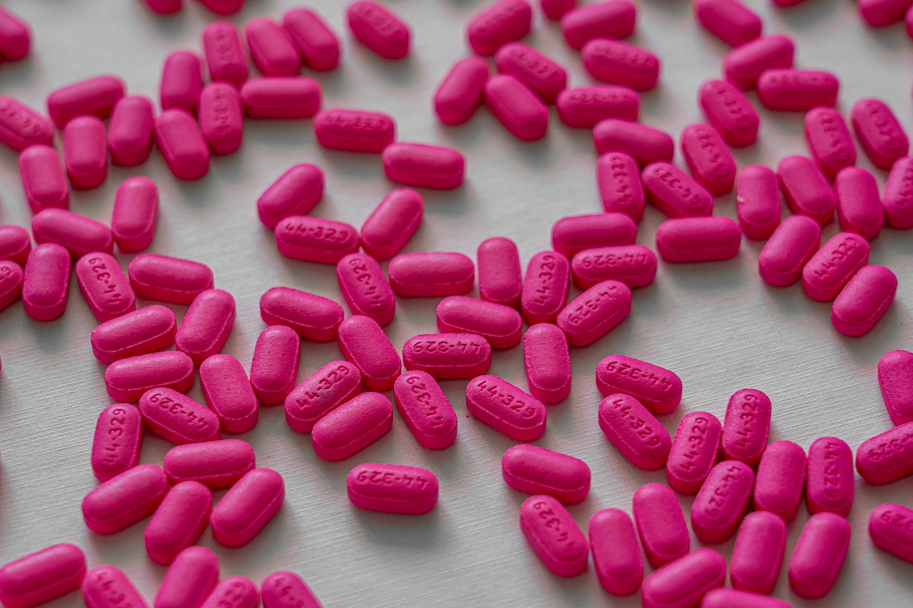 Close-up view of pink tablets scattered on a white table for medication and health treatment. - teen spring allergies