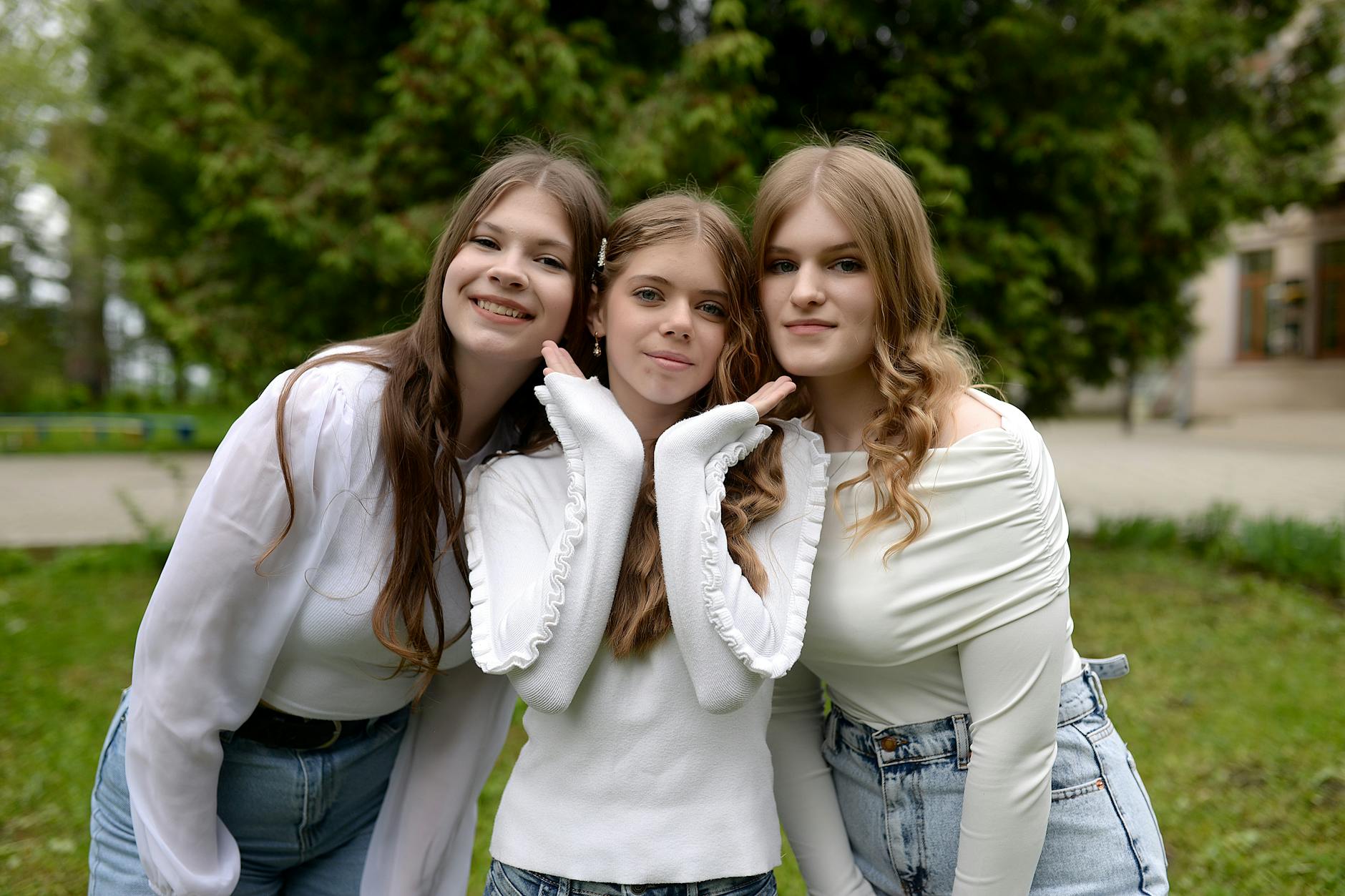 Three teenage girls in casual outfits smile while posing together outdoors in a park setting. - teen winter blues
