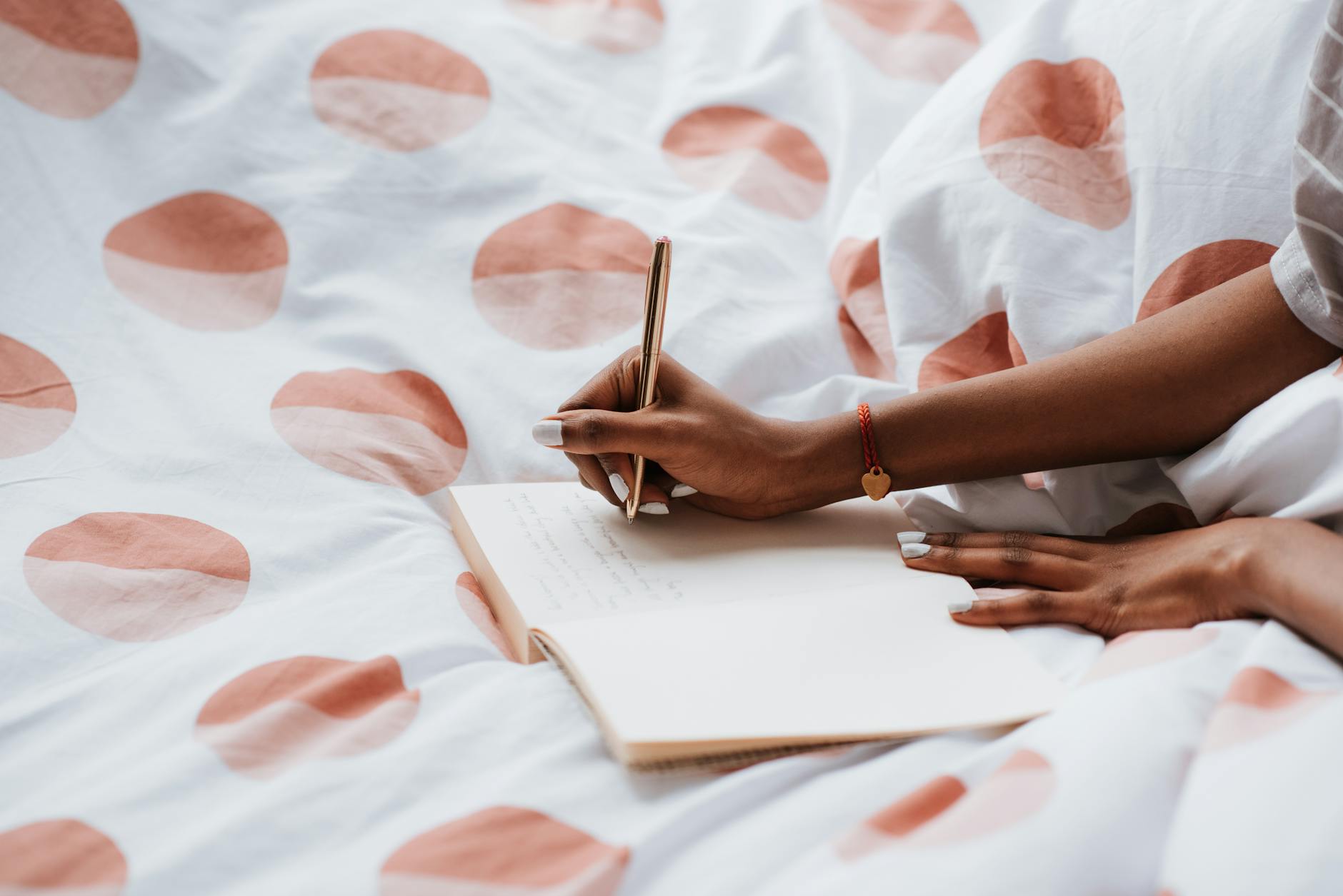 A woman journaling on a bed with polka dot sheets, creating a cozy atmosphere. - therapeutic journaling prompts