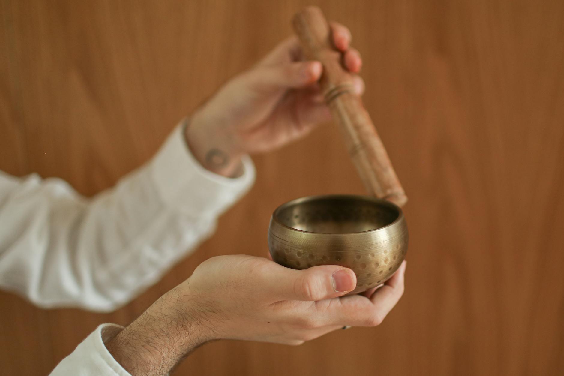 A detailed close-up of hands holding a Tibetan singing bowl for meditation and wellness. - therapy intentions