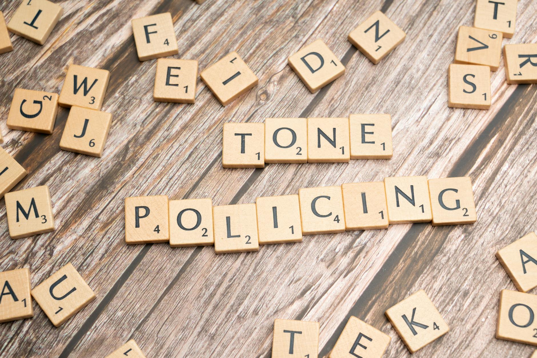 Scrabble tiles spelling 'Tone Policing' arranged on a rustic wooden surface, showcasing communication concepts. - toddler emotional regulation