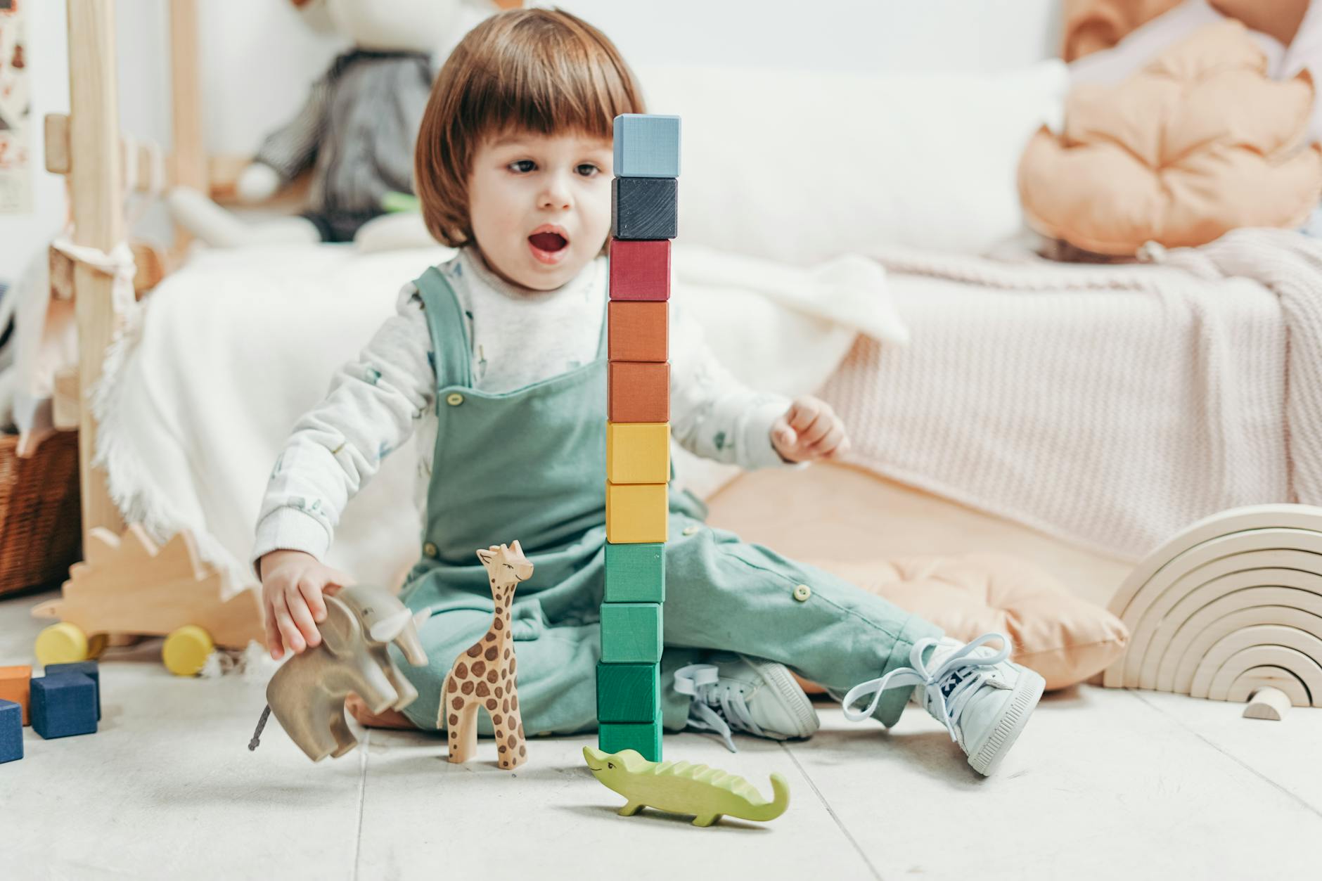 Adorable child playing with colorful wooden blocks and toy animals indoors. - toddler language development