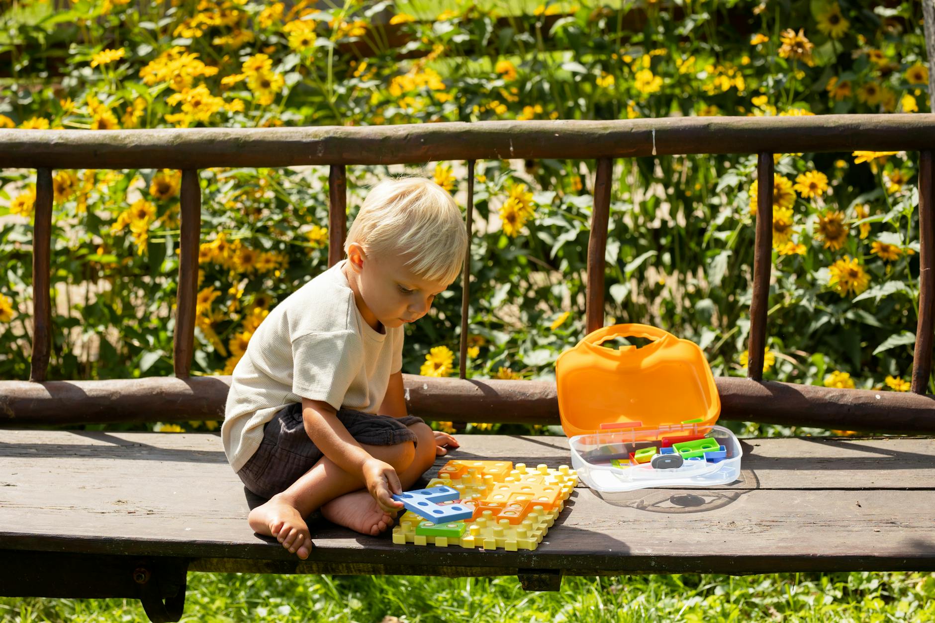 A young boy playing with a colorful puzzle outdoors on a sunny summer day. - toddler outdoor play