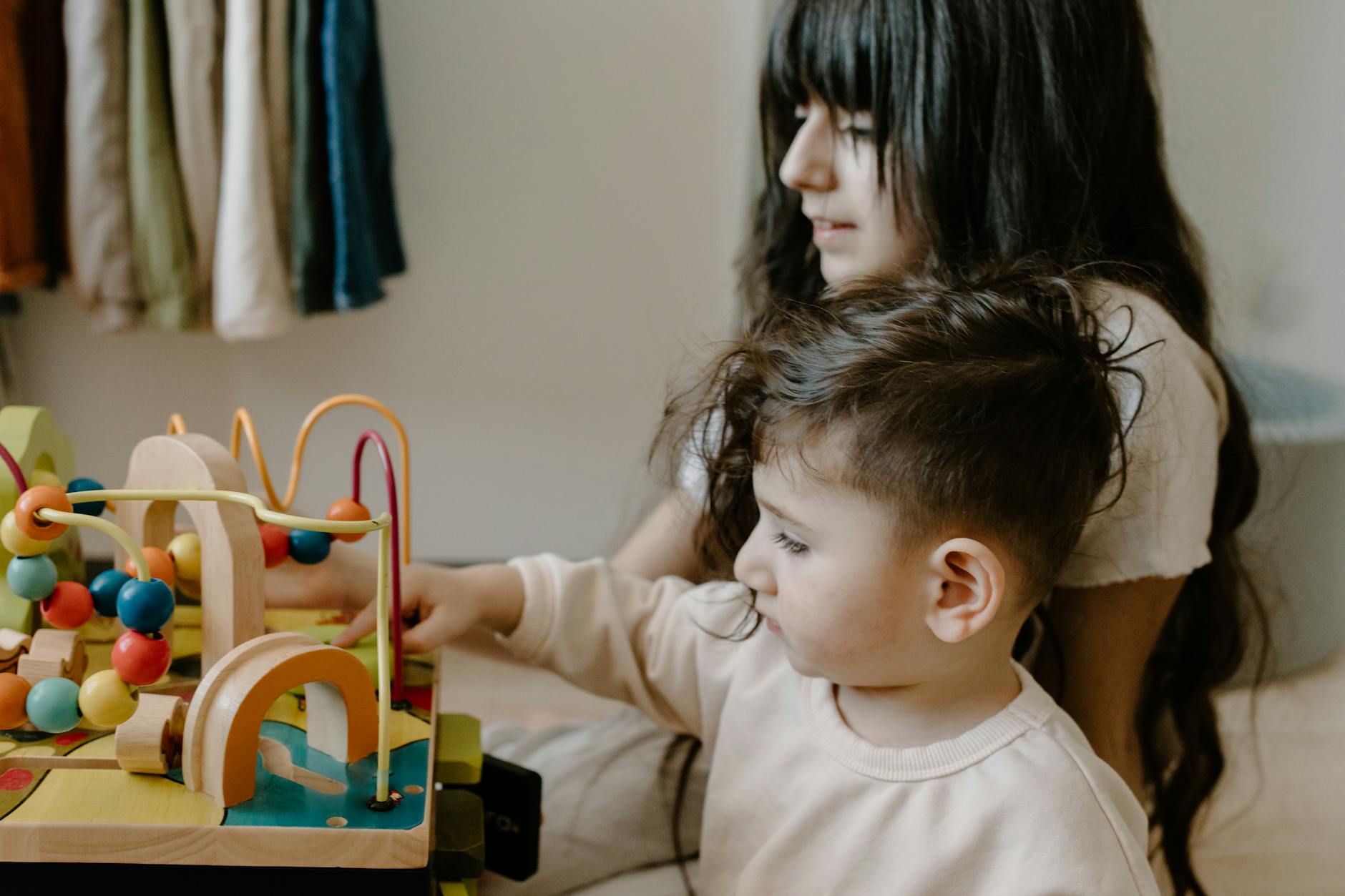 Two children engaged with wooden toys at a table, fostering imagination and playtime. - toddler playdate skills