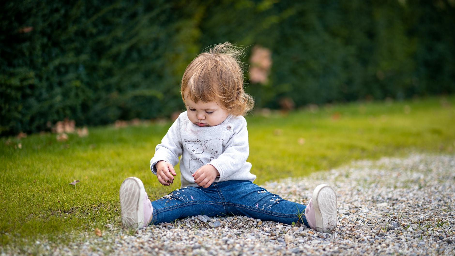A cute toddler sitting on grass in Vienna enjoying playtime outdoors, showcasing childhood joy. - toddler sensory play