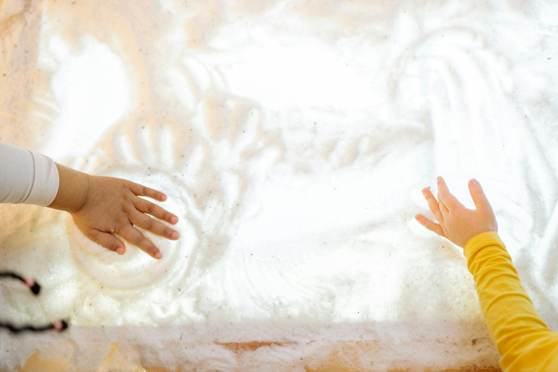 Two children interacting with a textured illuminated surface, engaging sensory play. - toddler sensory play