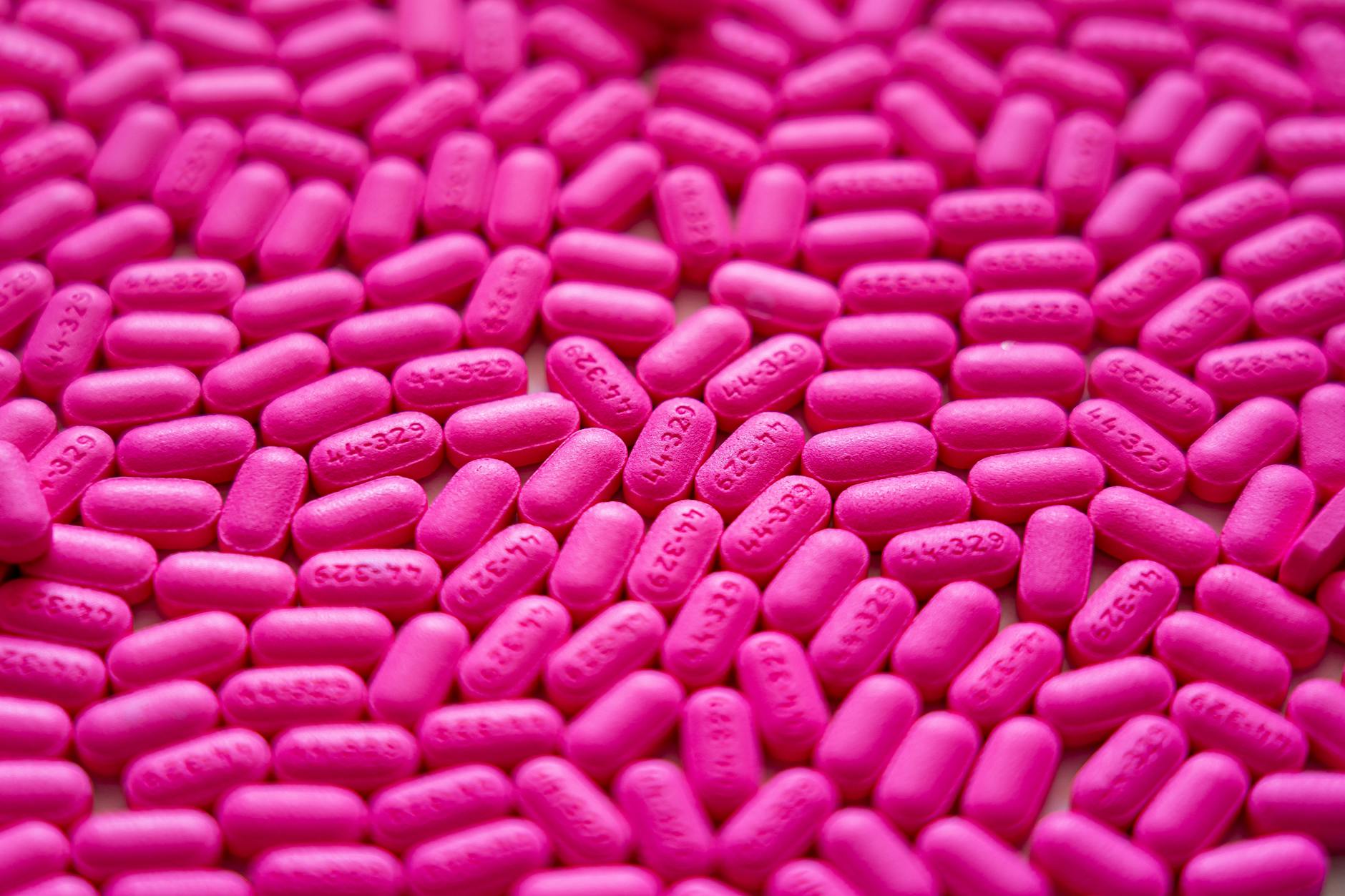 Bright pink antihistamine pills scattered for allergy treatment visualization. - toddler spring allergies