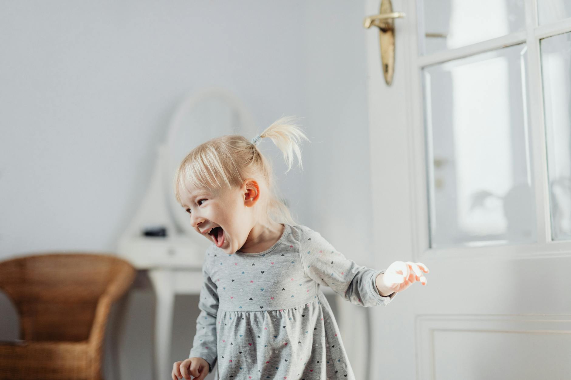 Laughing toddler in a light-filled room exuding happiness and innocence. - toddler spring energy