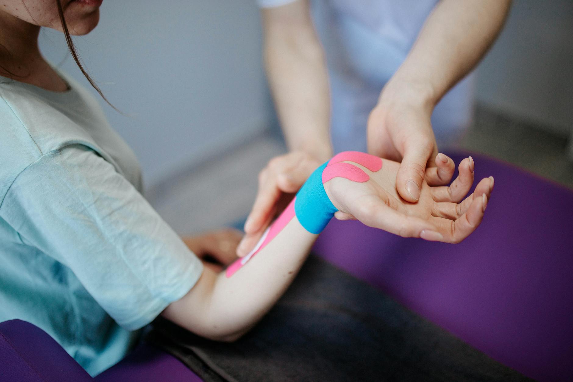 Close-up of a therapist applying kinesio tape for pain relief during a therapy session. - winter blues treatment