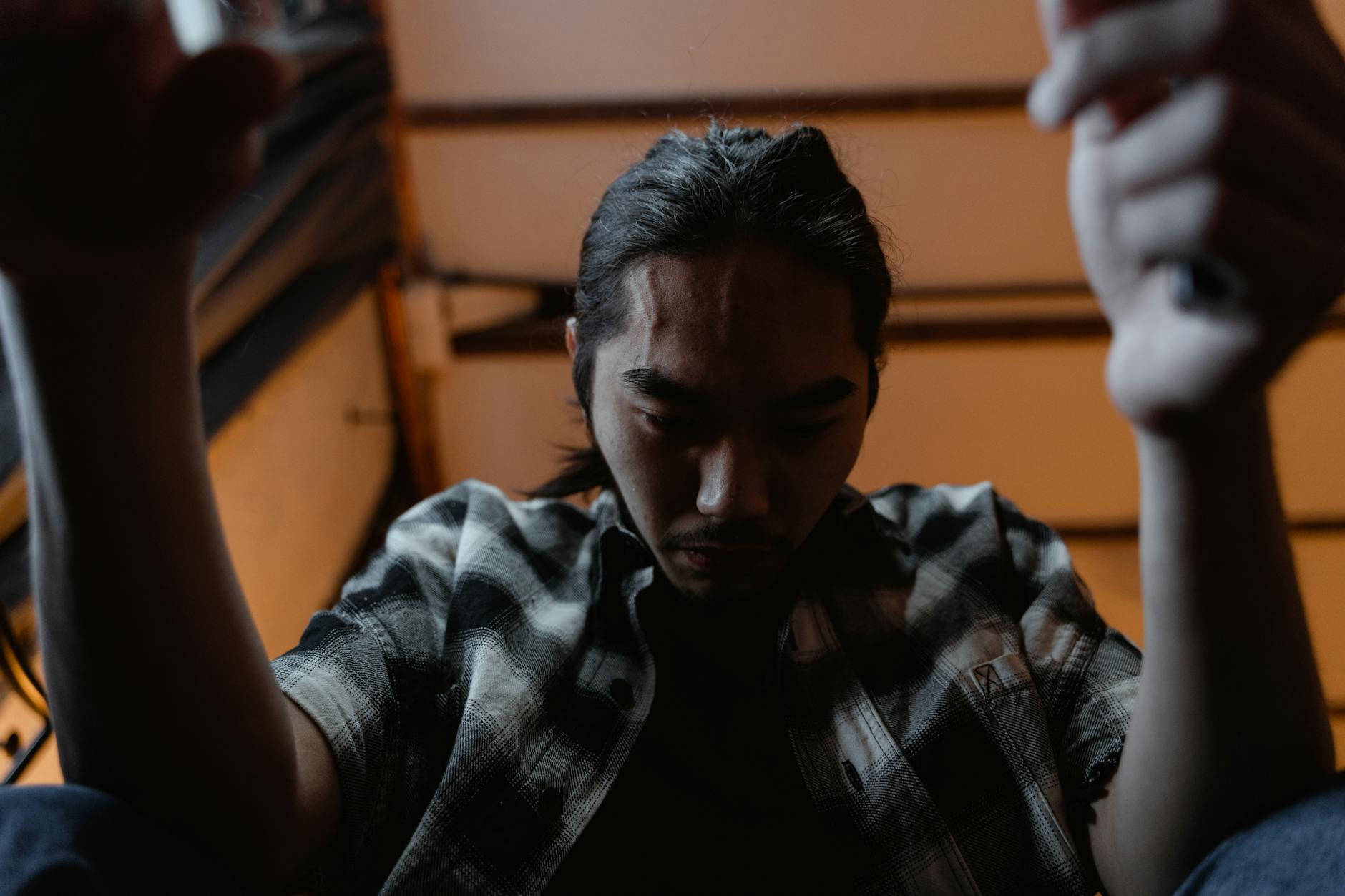 A young man sitting indoors, expressing deep emotion and contemplation. - winter depression mindfulness