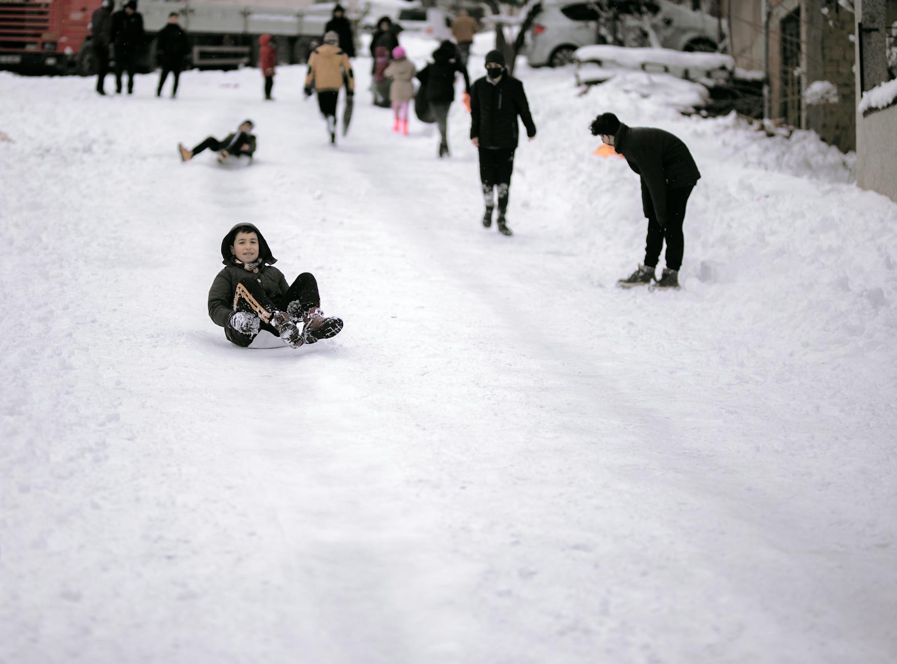 Kids enjoying sledding on a snowy street in Istanbul, Turkey. Winter fun and leisure activity. - winter kids activities