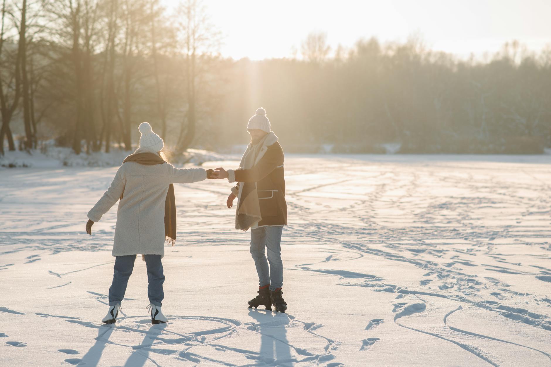Happy couple enjoying a sunny winter day ice skating on a snow-covered lake. - winter relationship activities