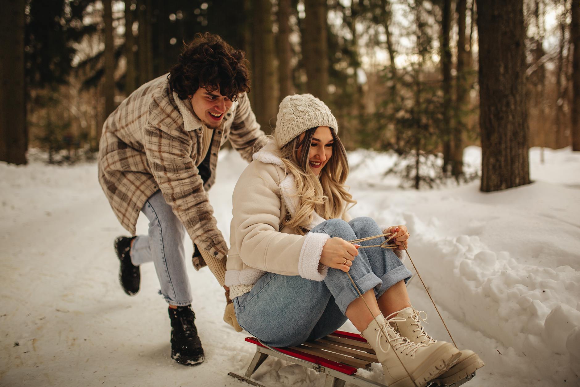 A joyful couple sledding in a snowy Moscow forest, highlighting winter fun and love. - winter relationship activities