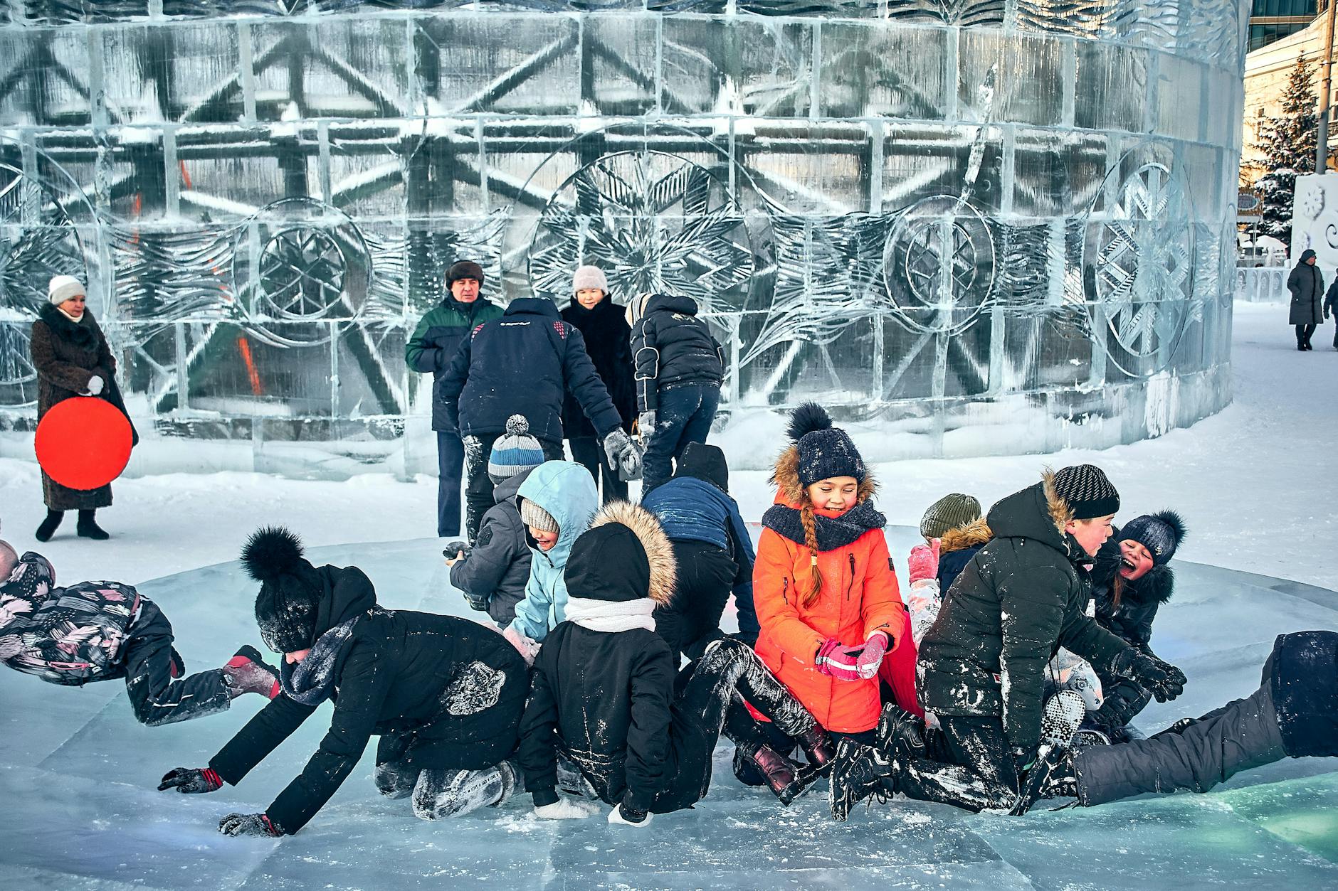Group of children enjoying a snowy day playing on an ice sculpture in a winter park with warm clothing. - winter sleep children