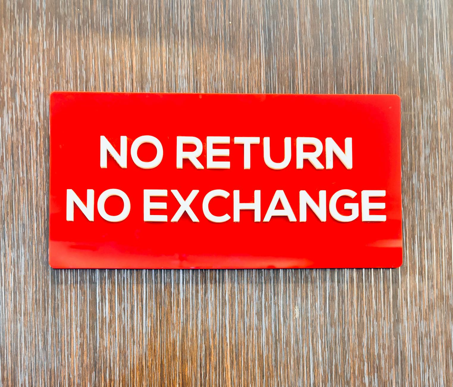 Bold red sign with 'No Return No Exchange' message on a wooden backdrop. - workplace dating policy