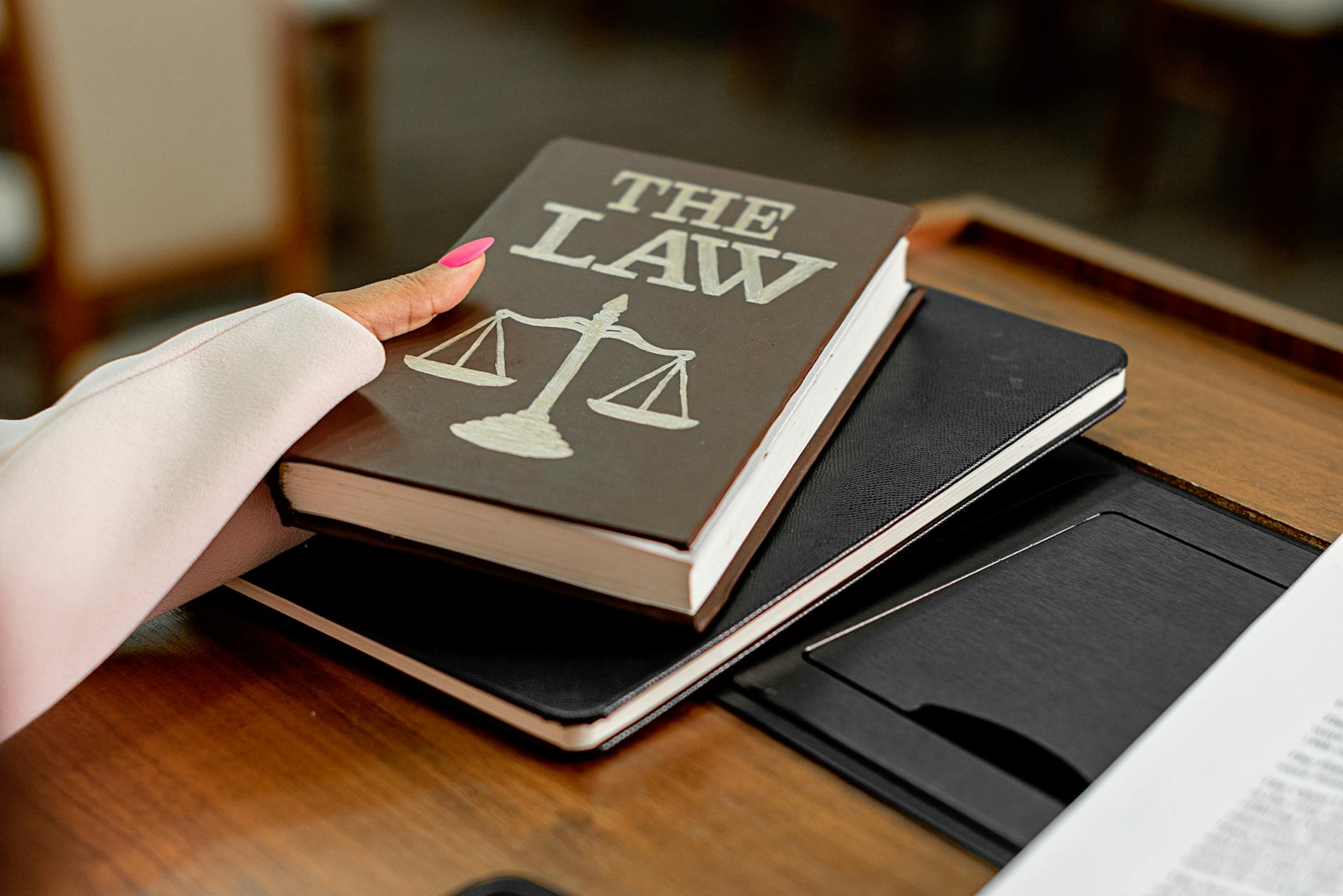 Closeup image of a law book titled 'The Law' on a wooden desk with scales of justice. - are workplace relationships legal