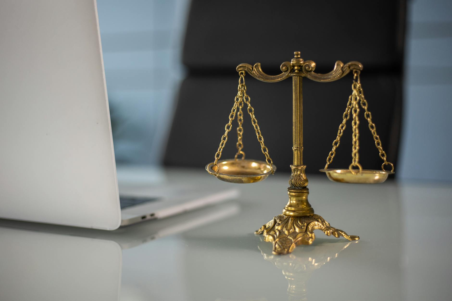 Golden justice scales on a desk beside a laptop, symbolizing law and balance. - are workplace relationships legal