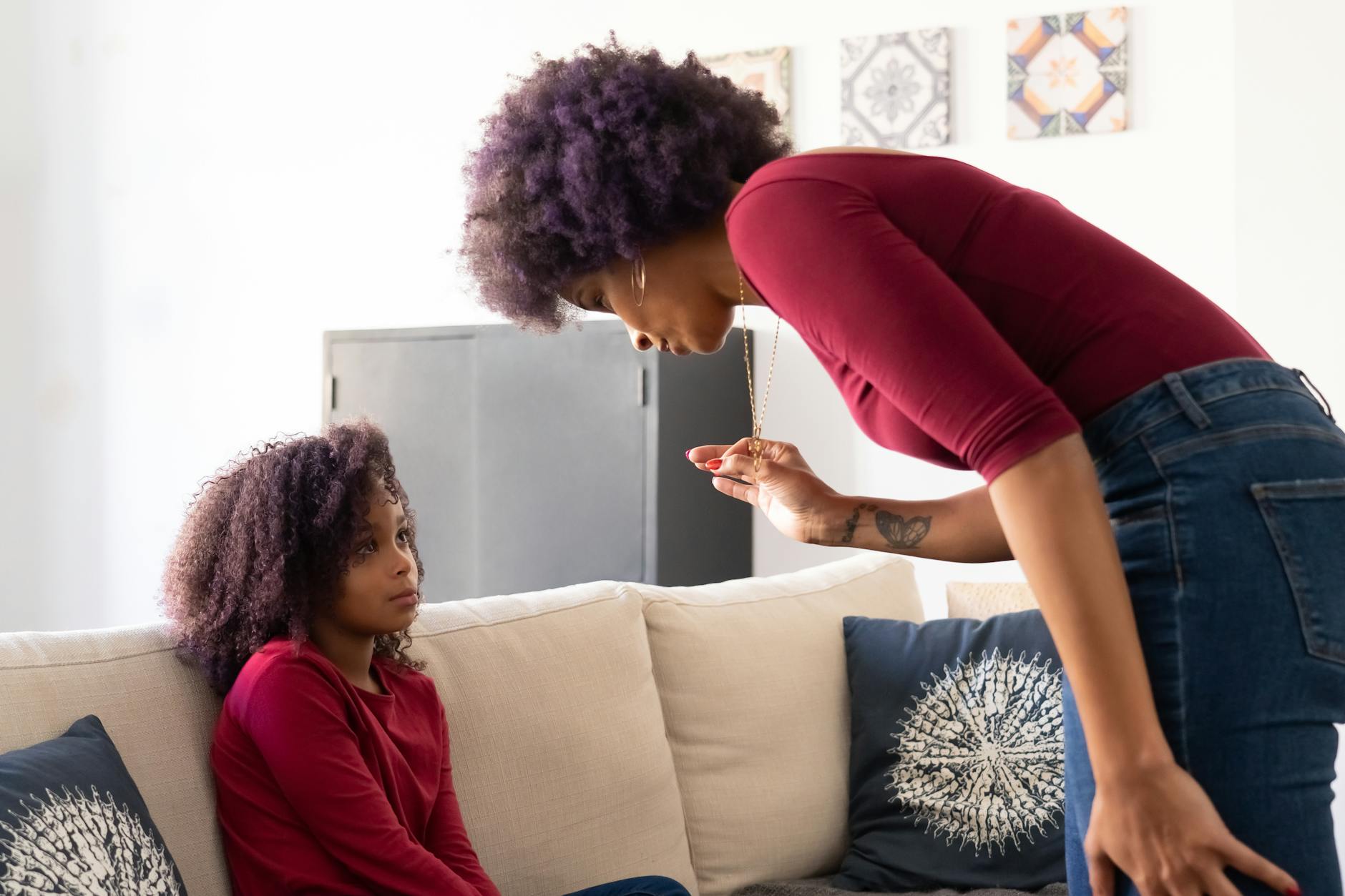 A mother and daughter with afro hair sit on a couch having a serious conversation at home. - active listening parents