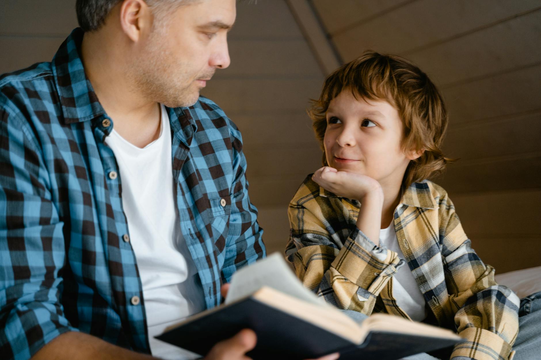 A father and son enjoy a cozy bedtime story together in a warm, indoor setting. - active listening parents