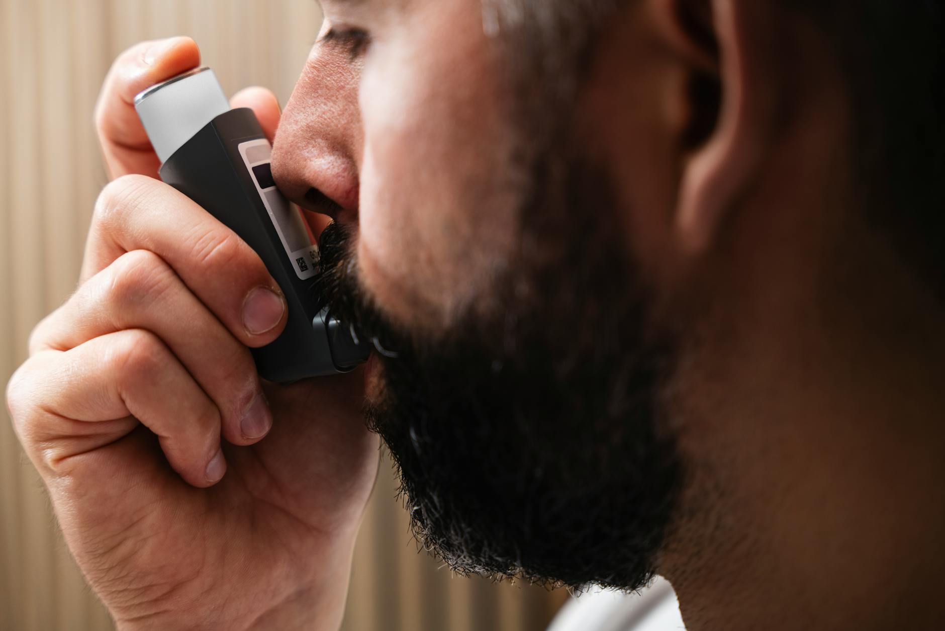 A close-up image of a man using an inhaler, highlighting respiratory health concepts. - allergy anxiety relief