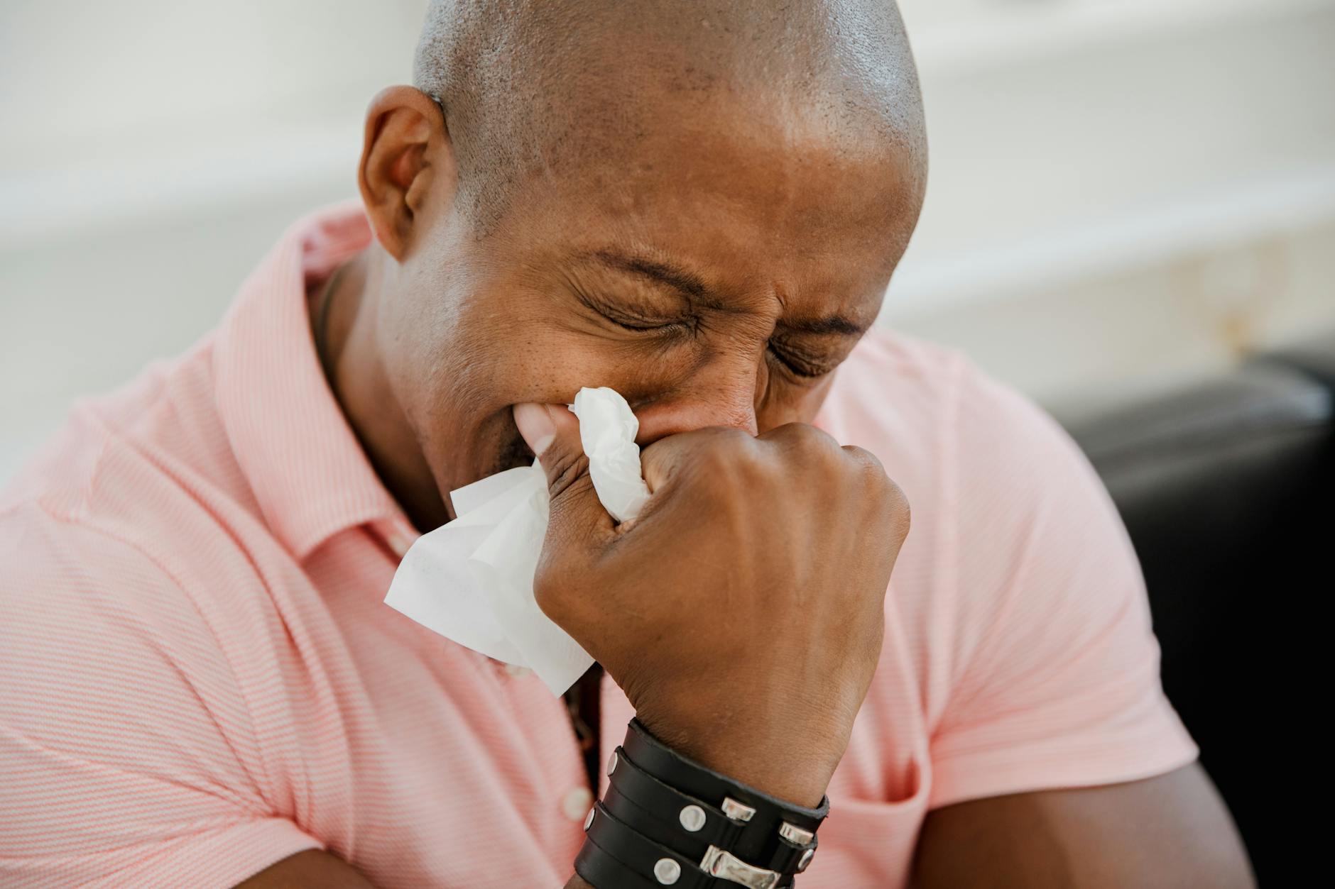 A close-up image of a black man in a pink shirt expressing strong emotions. - allergy stress relief
