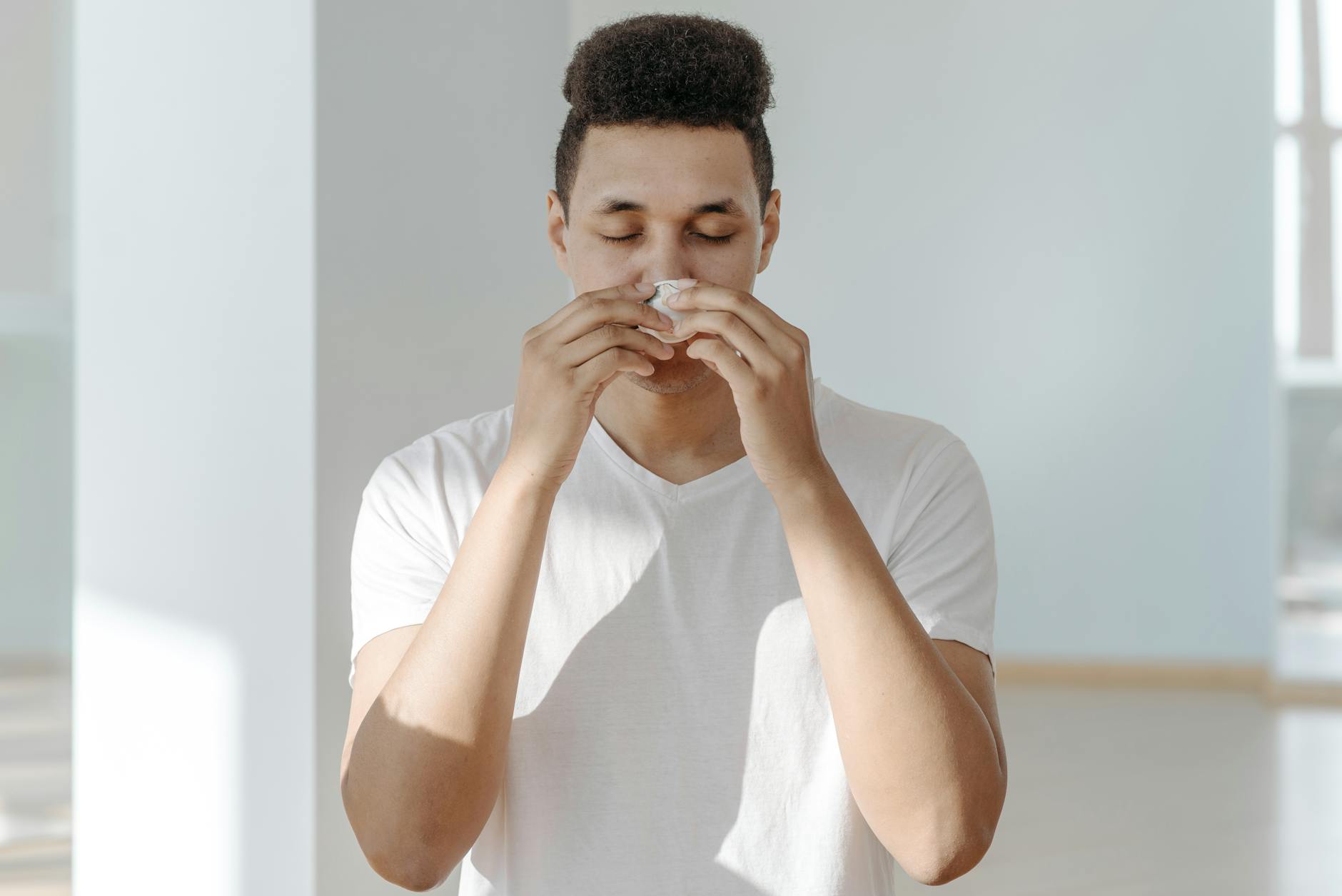 A man sneezing into a tissue, illustrating symptoms of flu or allergies. - allergy stress relief