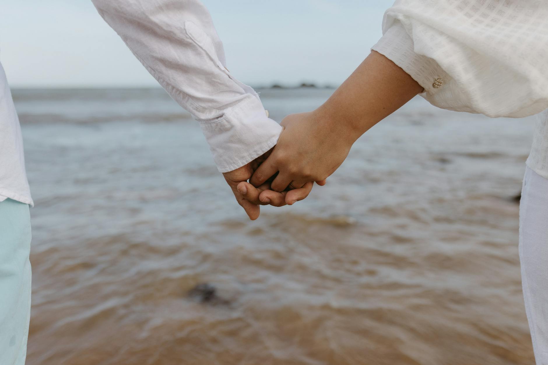A romantic moment of a couple holding hands by the seaside, symbolizing love and togetherness. - attachment styles explained