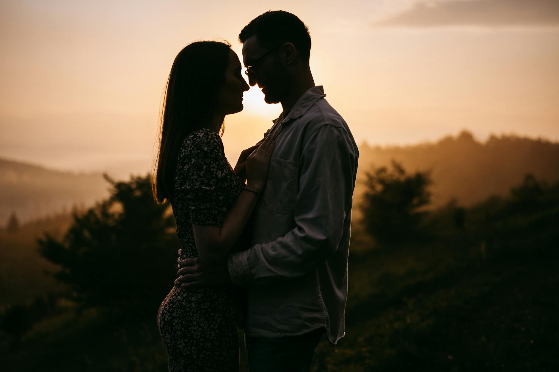 Silhouetted couple embracing romantically at sunrise in a mountainous landscape. - attachment styles explained